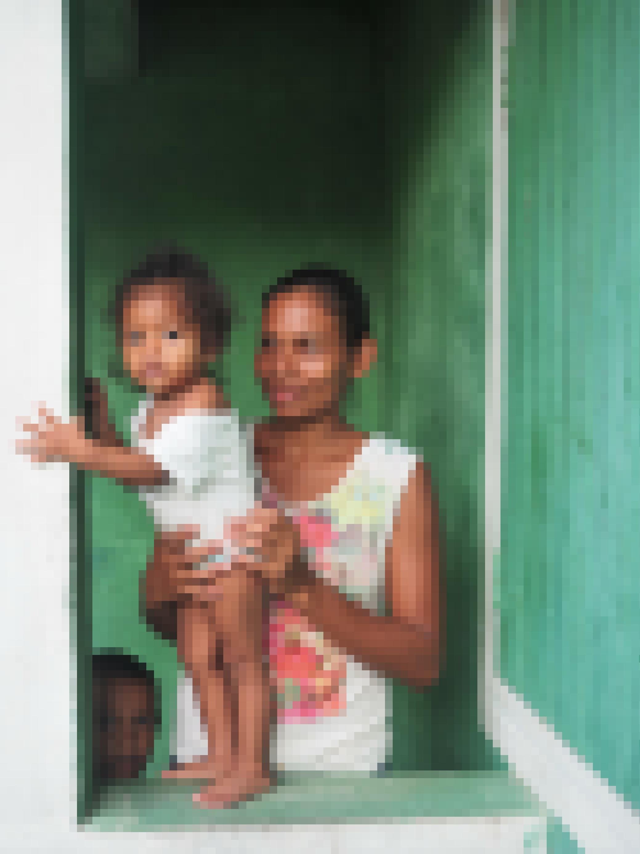 Eine junge Miskito Mutter mit ihren zwei Kindern am Fenster ihres hellgrün gestrichenen Wohnhauses in Wawa bar