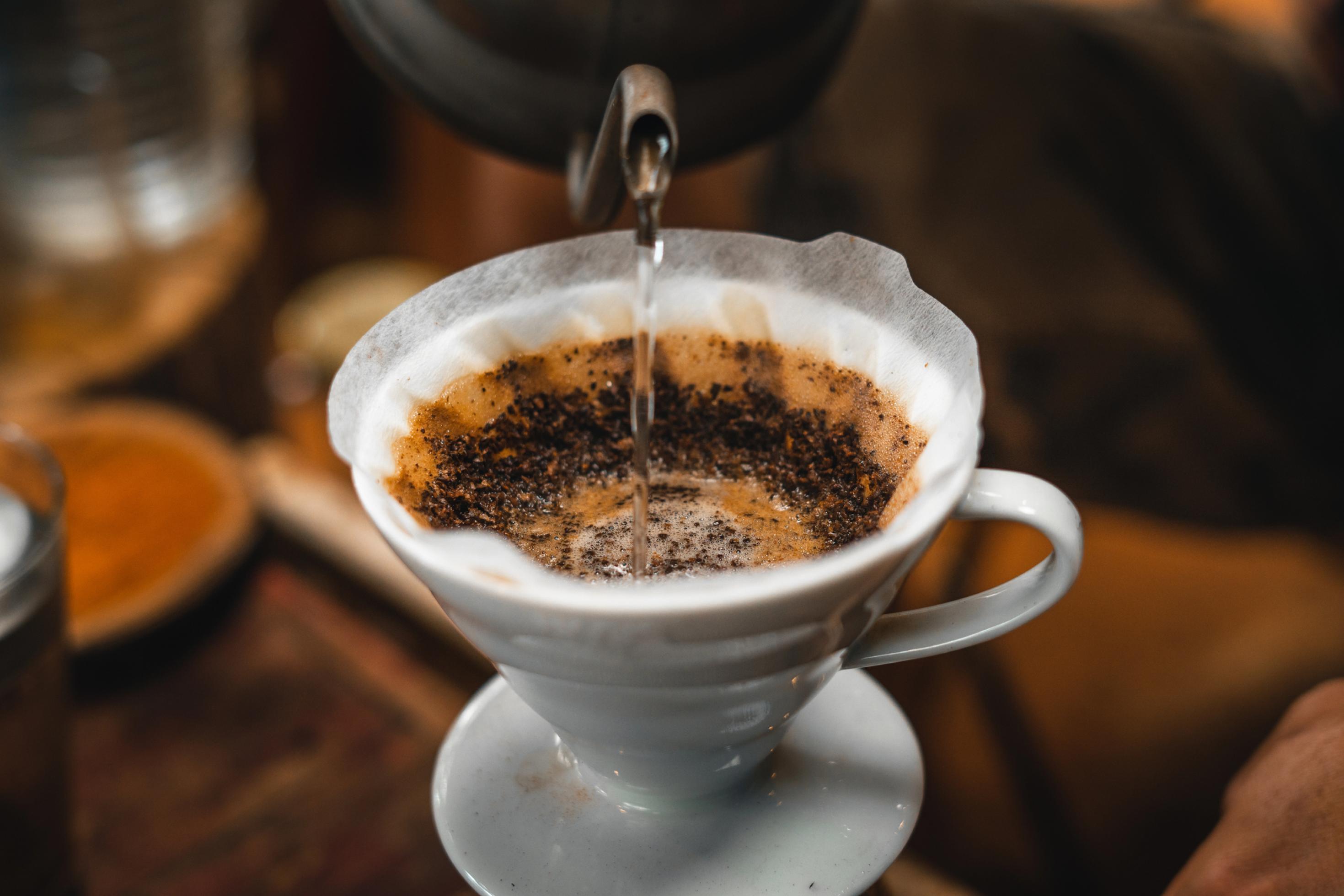 Halbnahe: Wasser wird in Kaffeefiltertüte gegossen.