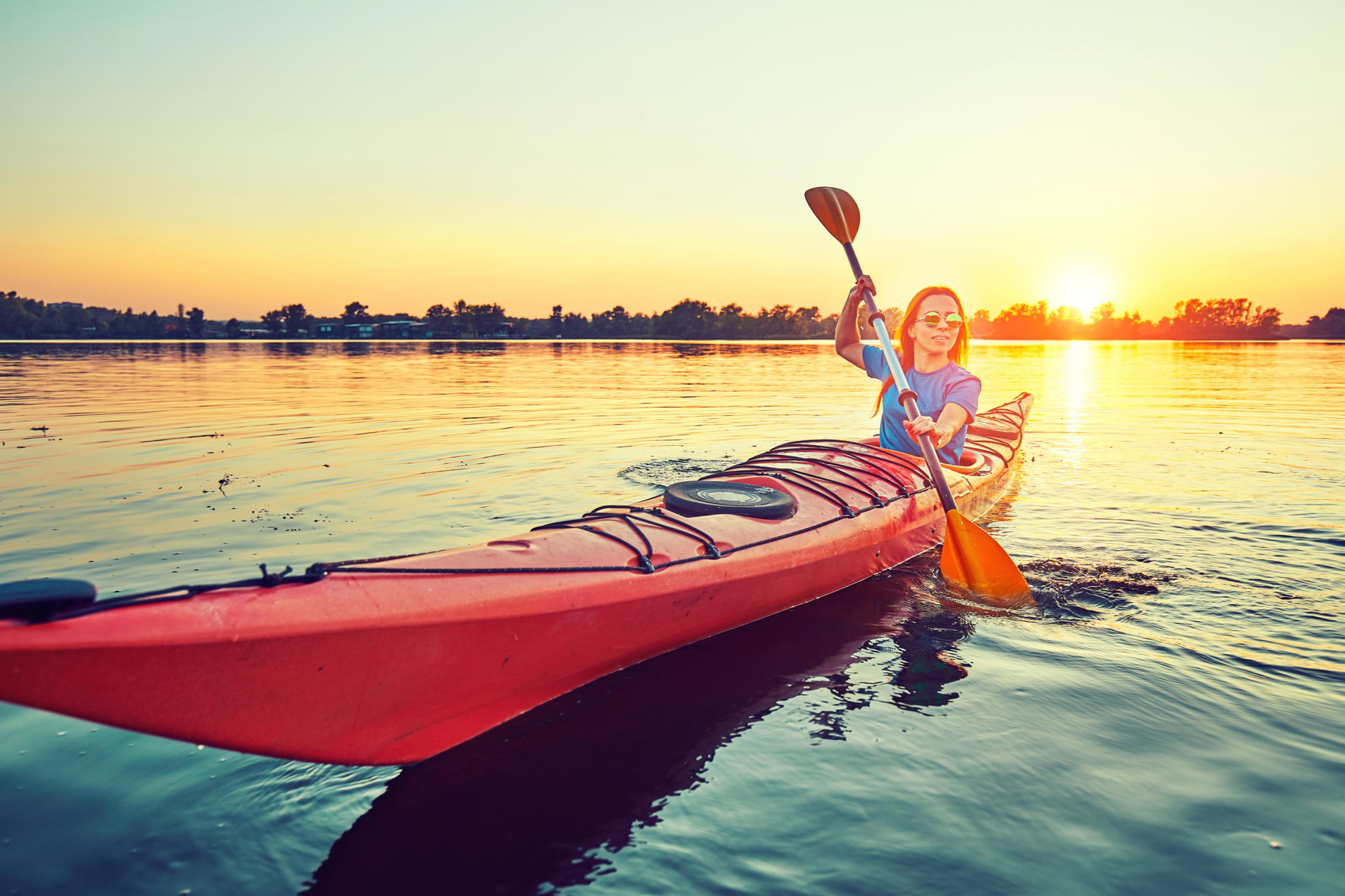 Eine Frau fährt Kayak. Sonnenuntergang.