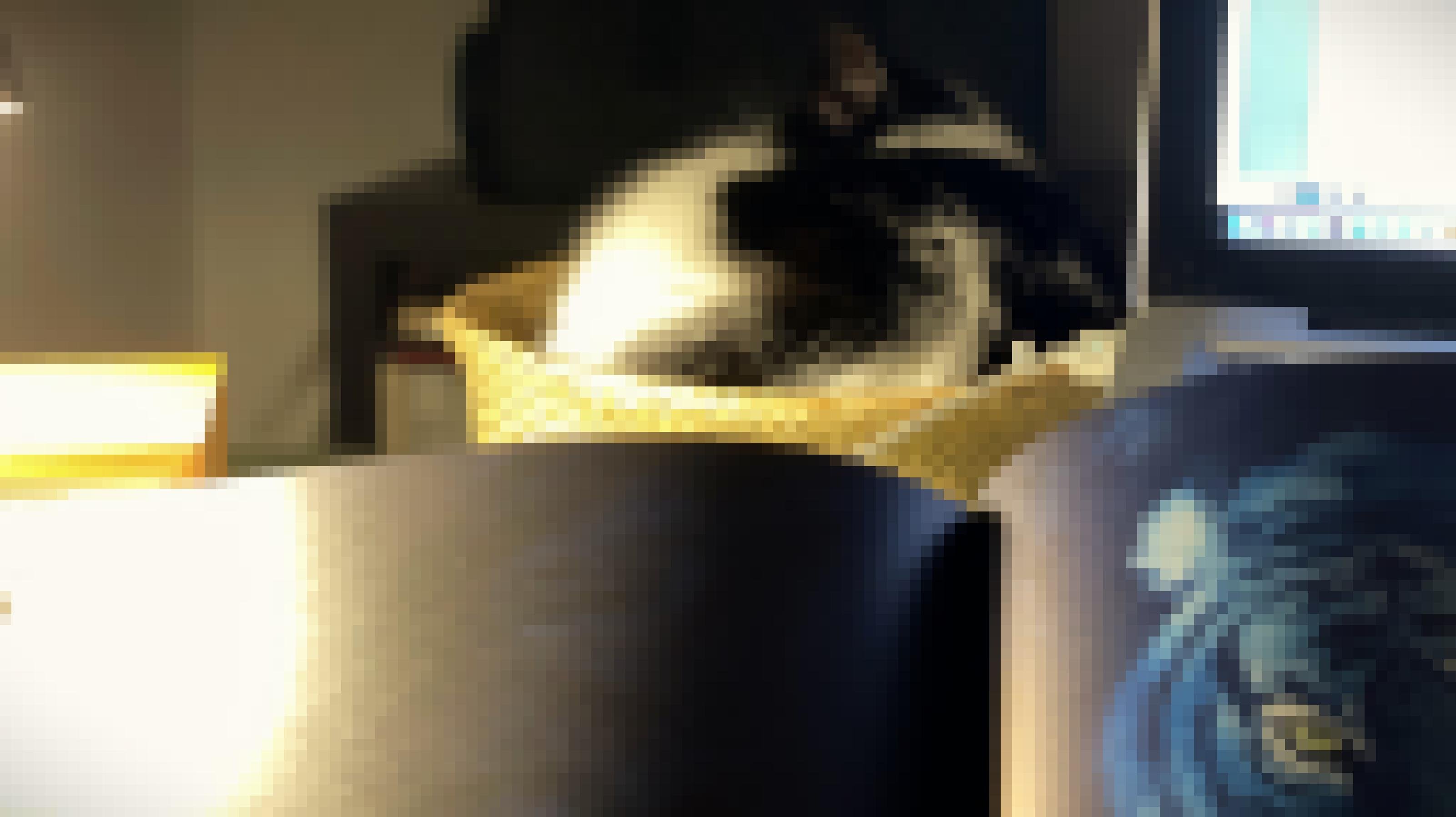 Eine schwarz-weiße Katze ist eingeschlafen. Sie hat sich zusammengerollt, ein Ohr ragt nach oben. Vor ihr ein Computermonitor und ein aufgeschlagenes Kinderbuch mit der Zeichnung eines Tigers..