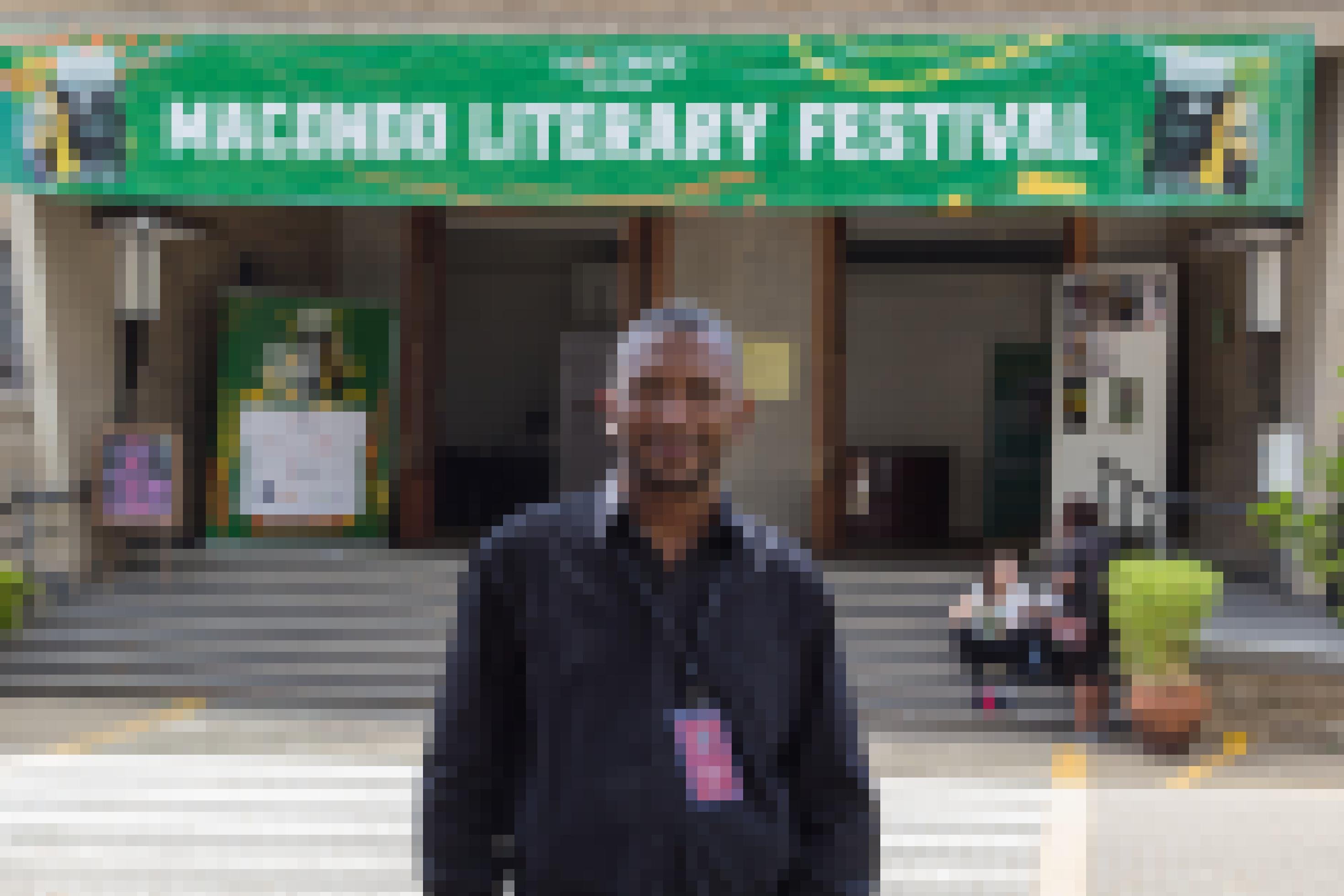Ein Mann steht vor dem Eingang eines Hauses. Über dem Eingang hängt ein Banner mit der Aufschrift „Macondo Literary Festival“.