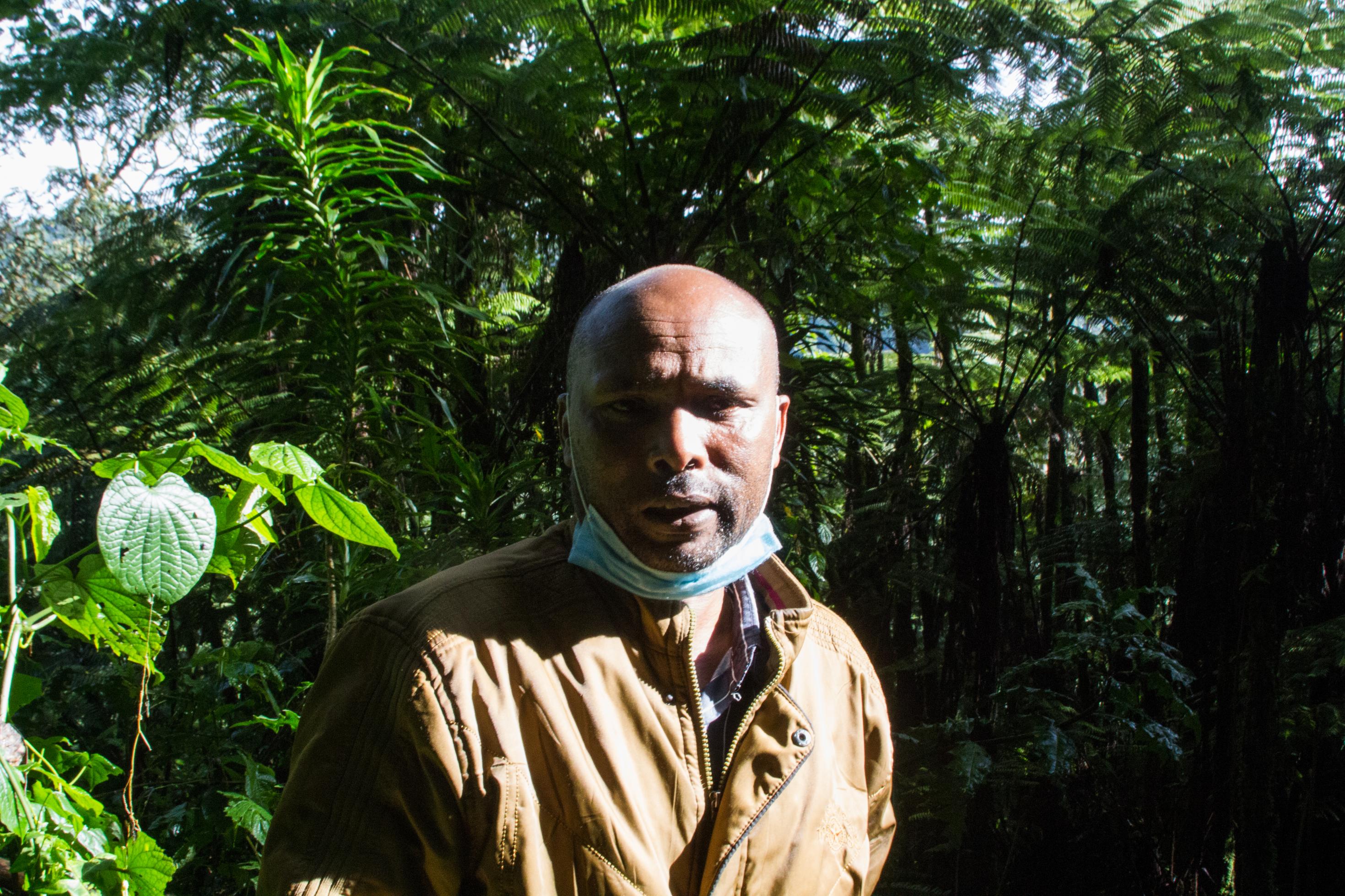 John Mutai im Sonnenlicht, im Hintergrund der Regenwald zu sehen.