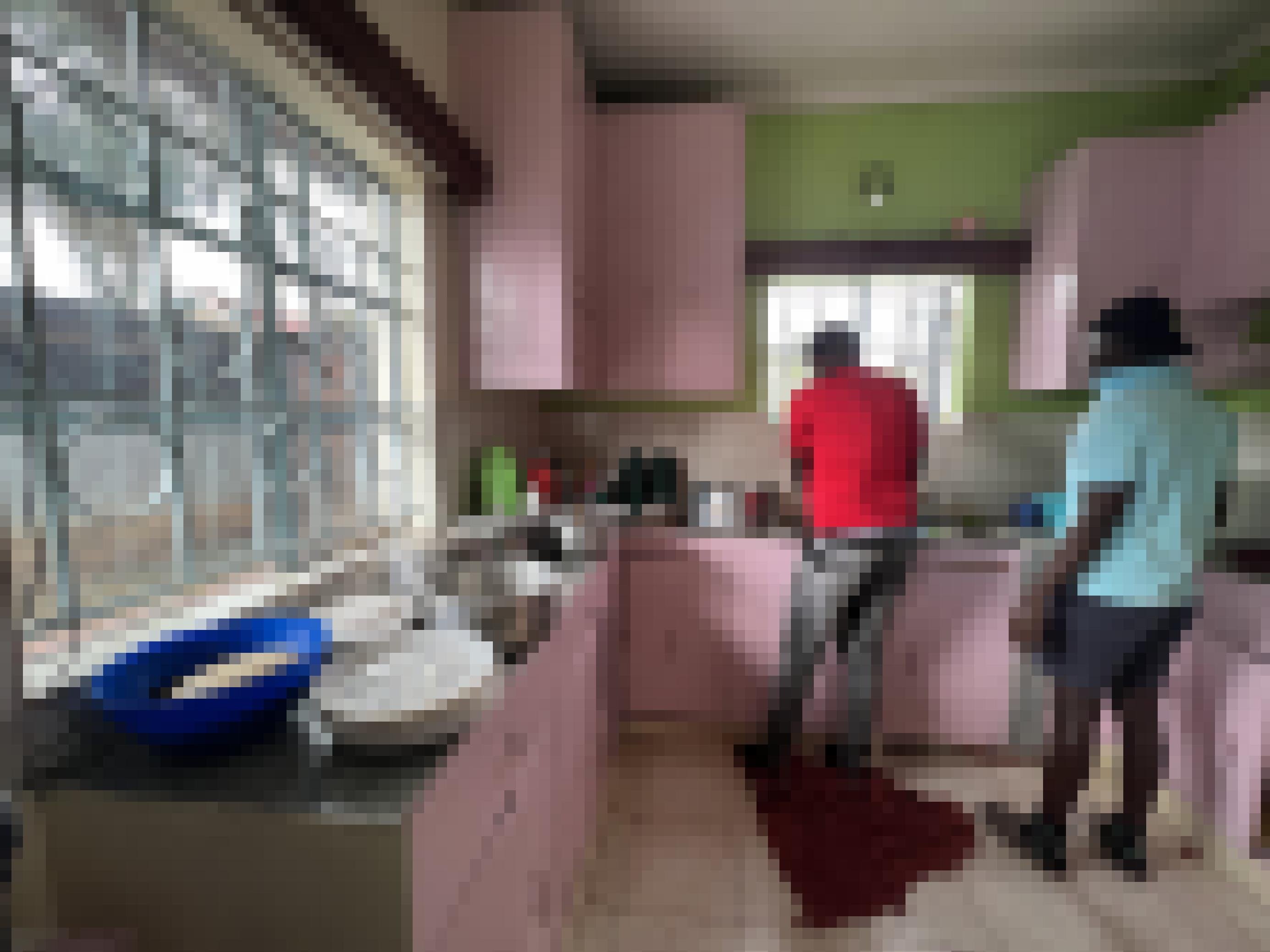 In der Küche des Hauses sind zwei Flüchtlinge von hinten zu sehen, sie sind offensichtlich dabei, eine Mahlzeit für mehrere Menschen vorzubereiten. Mehrere Töpfe sind schon wie für ein Buffet auf der Arbeitsplatte der Küche aufgebaut.