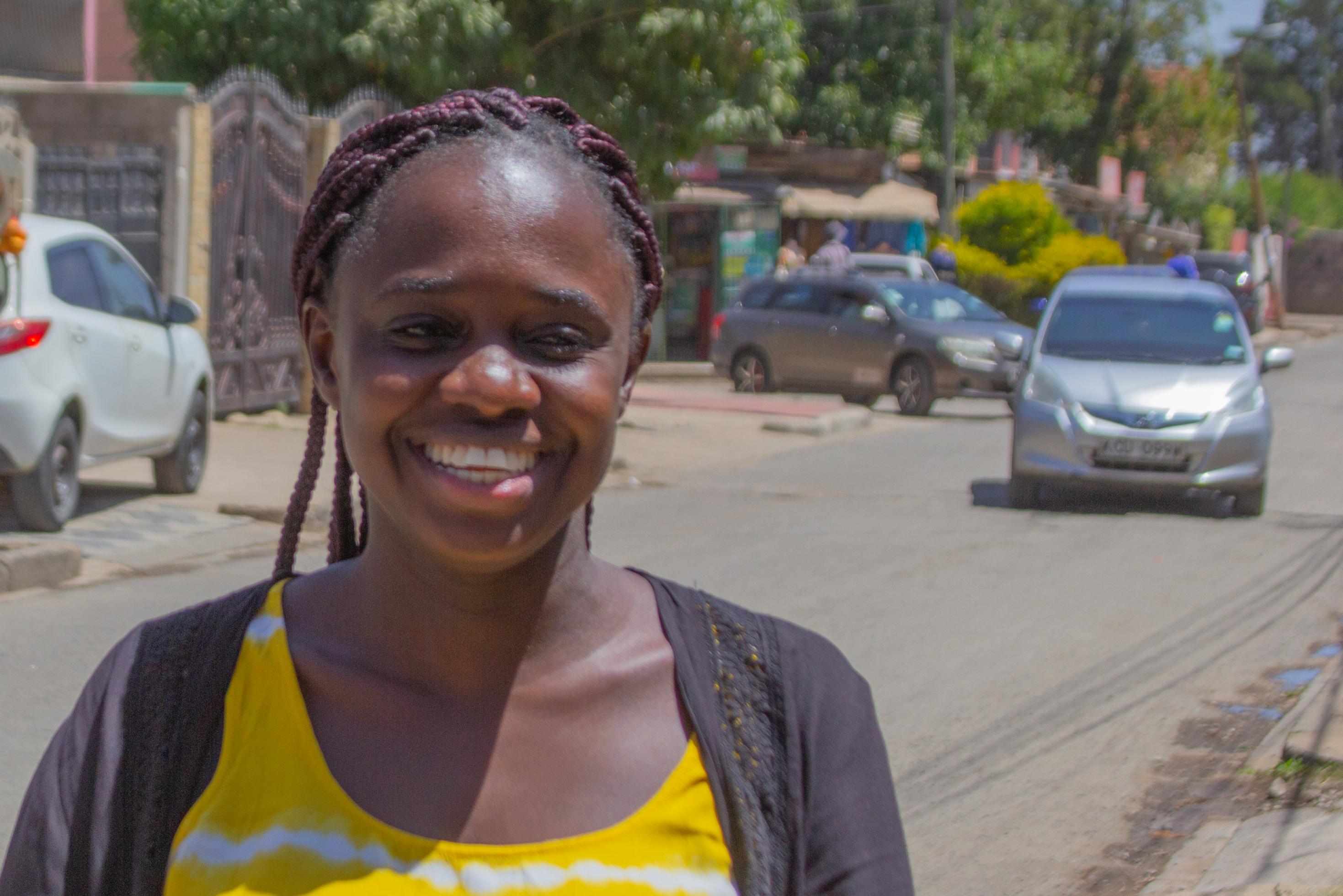 Mercy Otieno steht auf einer Strasse, lacht gewinnend.