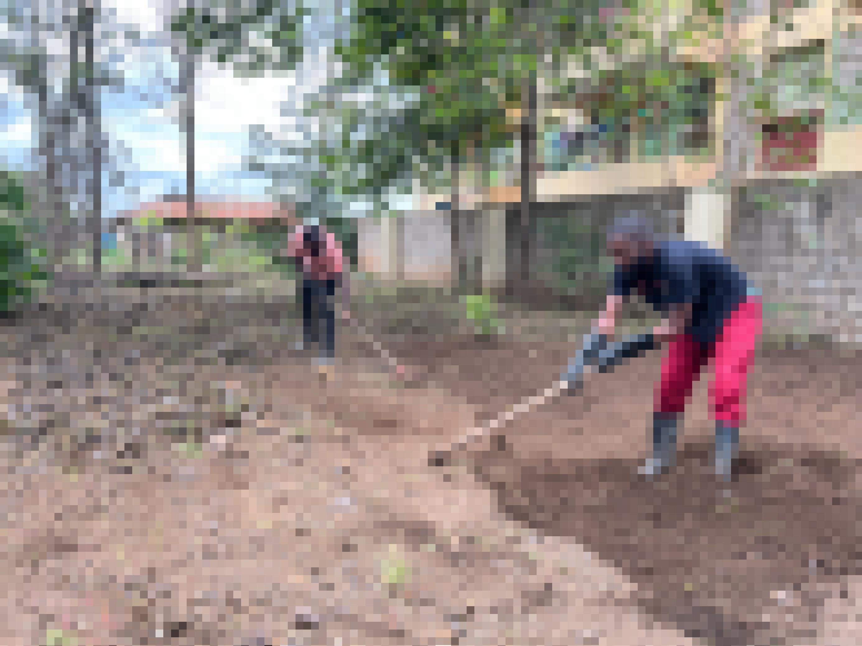 Zwei Männer sind mit Hacken dabei, den Garten umzugraben. Sie sind gebückt und nur von der Seite zu sehen.