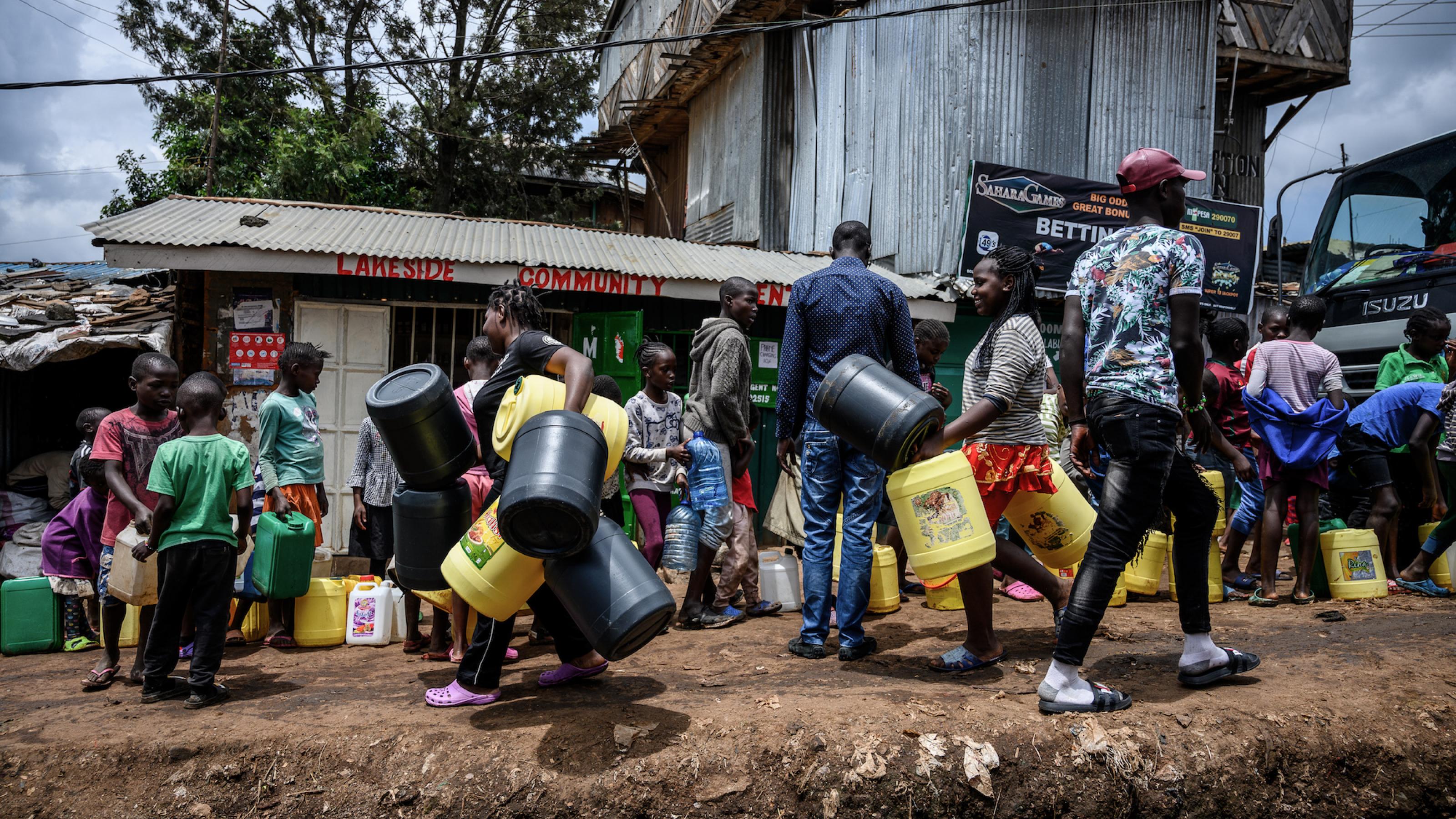 Das Bild zeigt Kenianer, die mit Wasserkanistern in einer Schlange stehen. Sie wollen sauberes Trinkwasser bekommen.