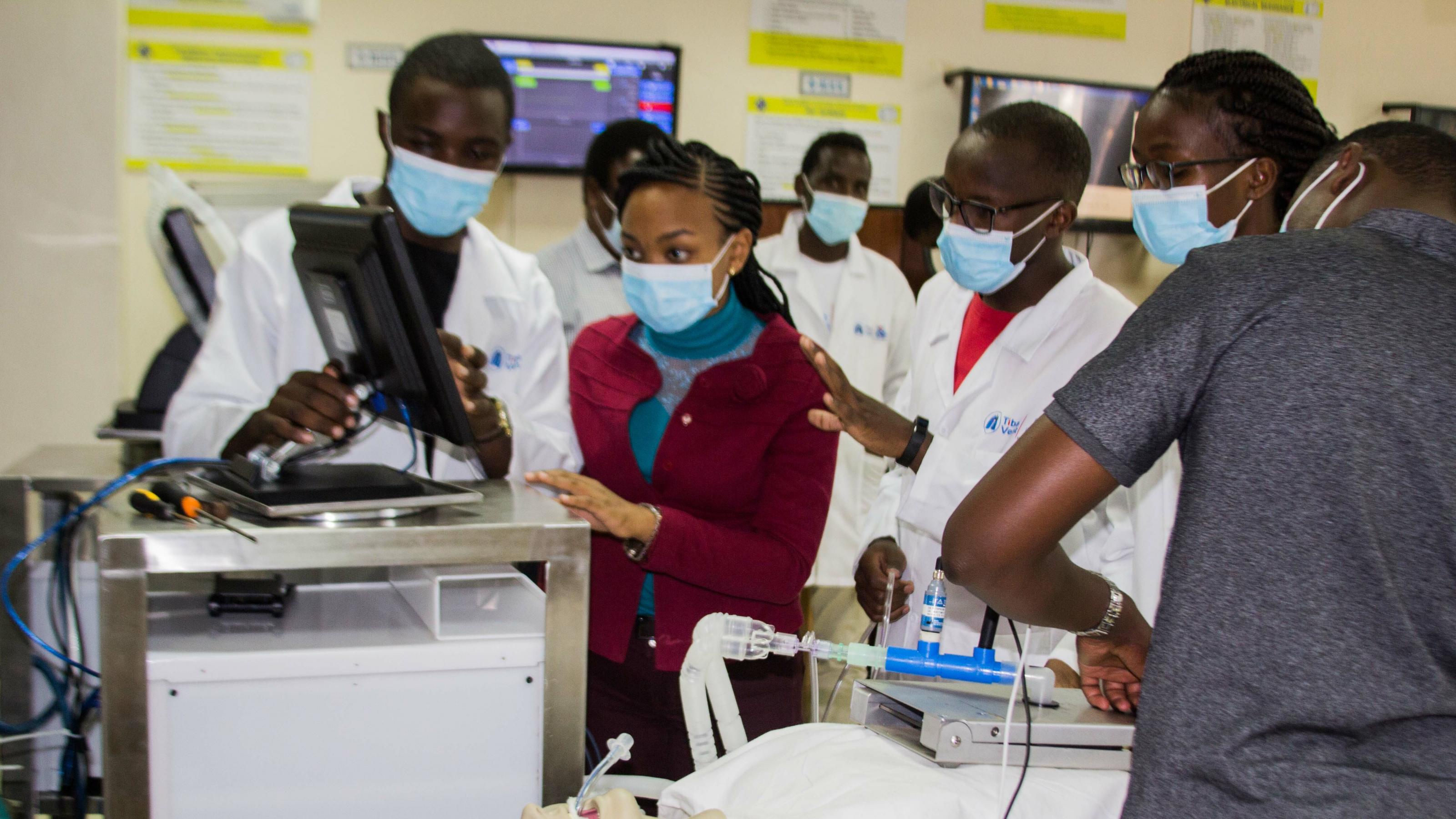 Studierende der Kenyatta-Universität stehen vor einem Dummy, der an einen Prototypen eines Beatmungsgeräts angeschlossen ist.