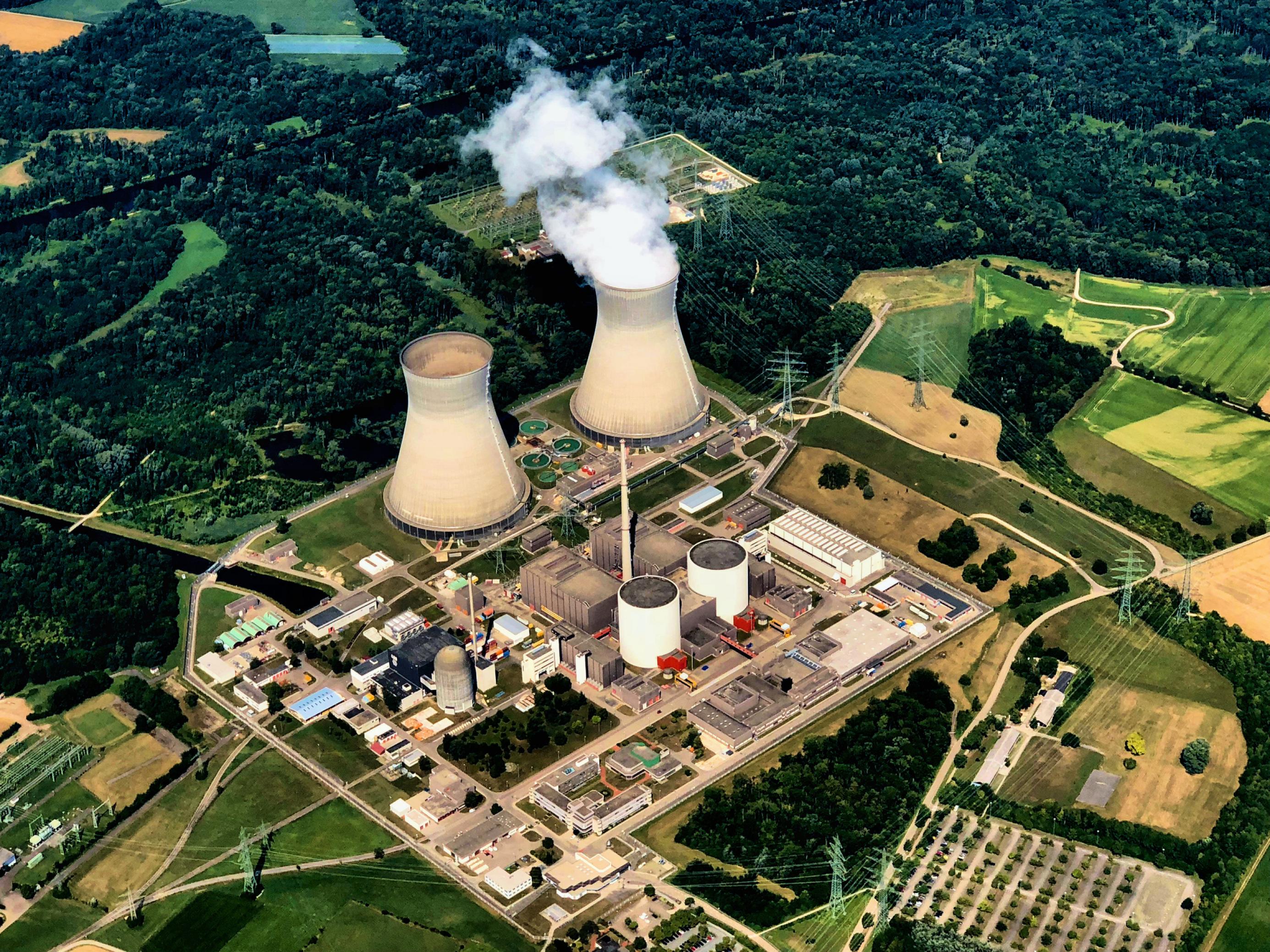Das Kraftwerksgelände aus der Luft mit seinen Kühltürmen und dem Reaktorblock, umgeben von Wald und Wiesen.