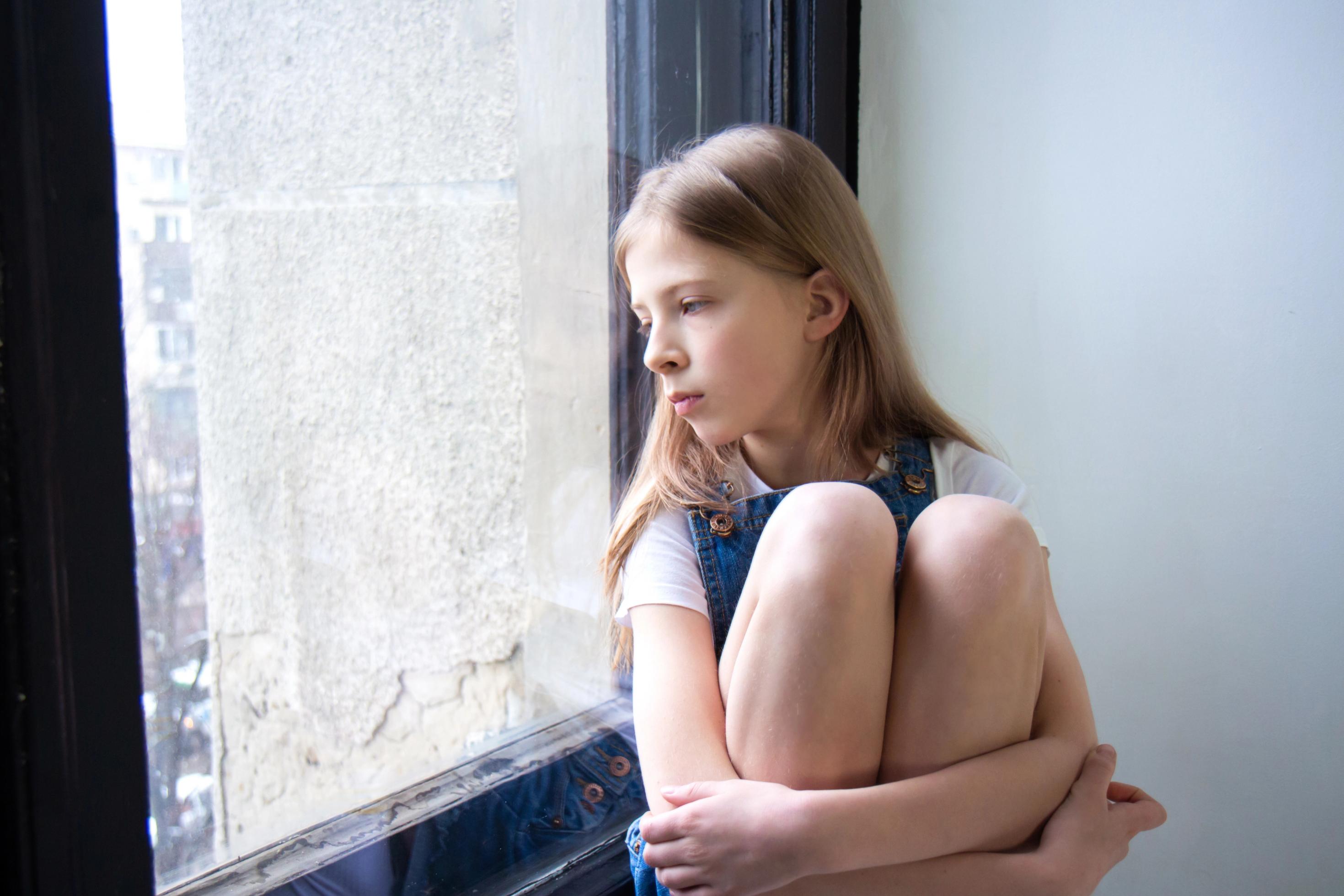 Ein Mädchen sitzt an einer Fensterscheibe