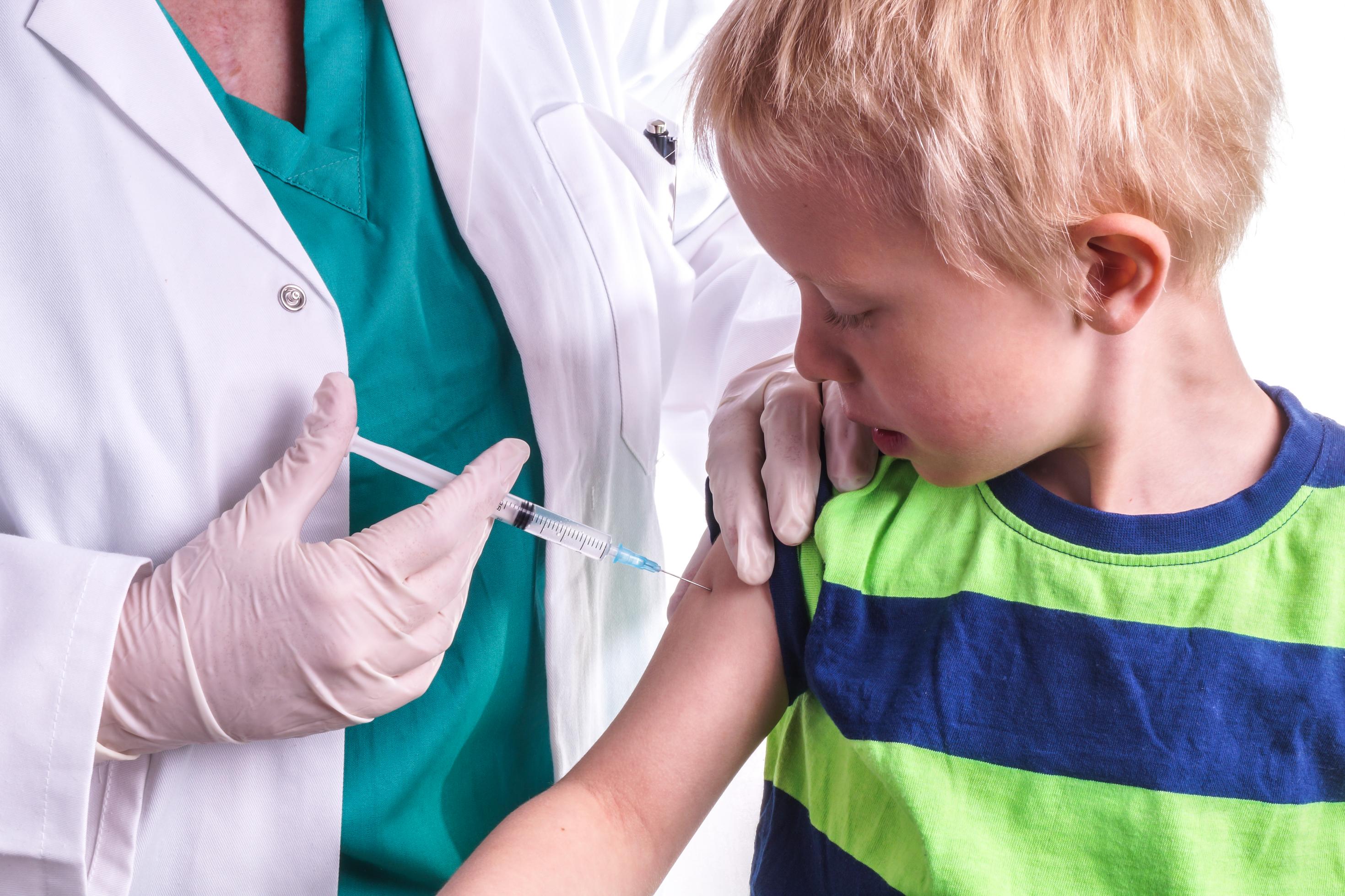 Ein kleiner Junge erhält eine Injektion mit einer Spritze in den Oberarm.