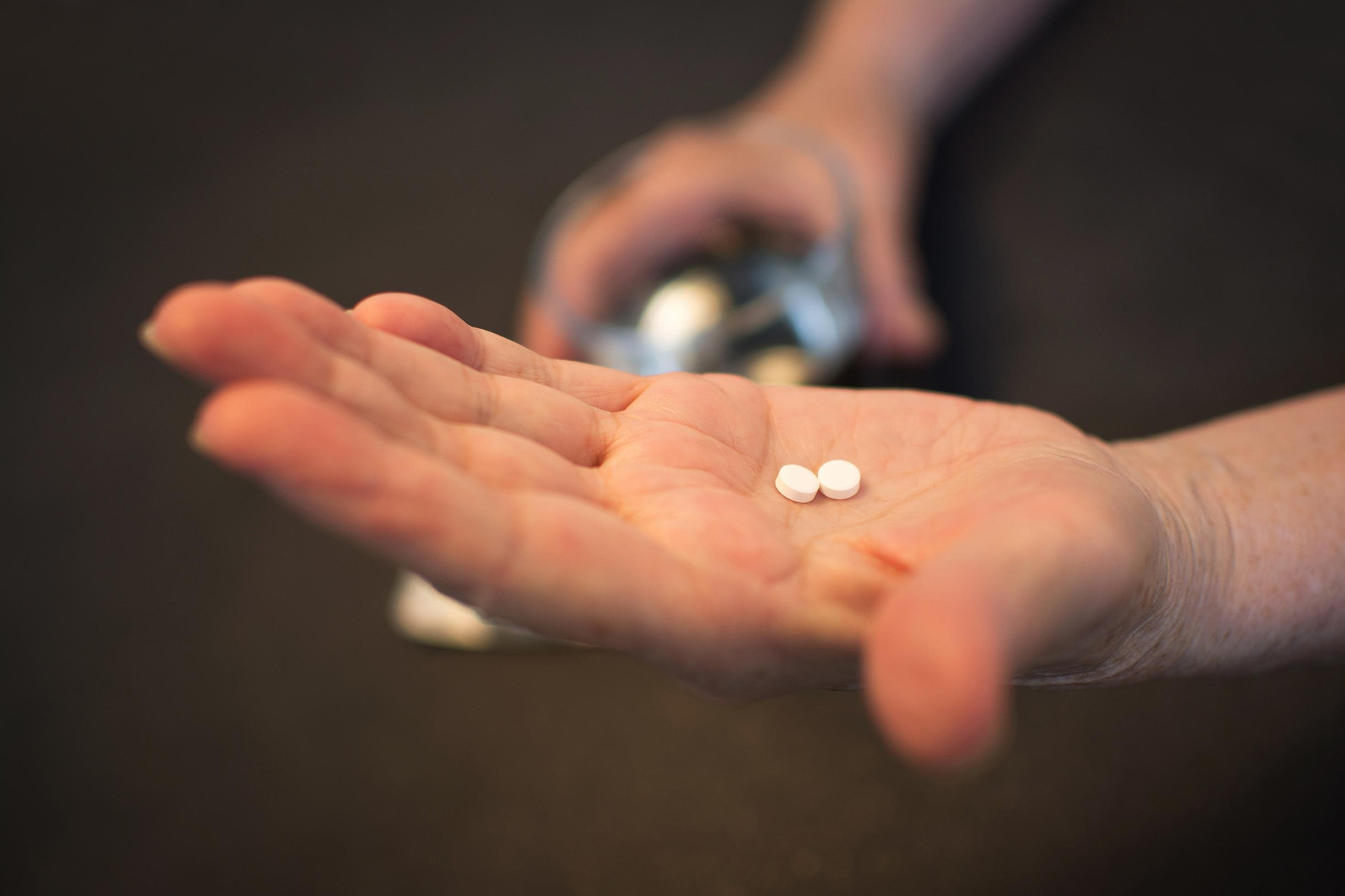 Auf der Hand eines Mannes liegen zwei Tabletten.