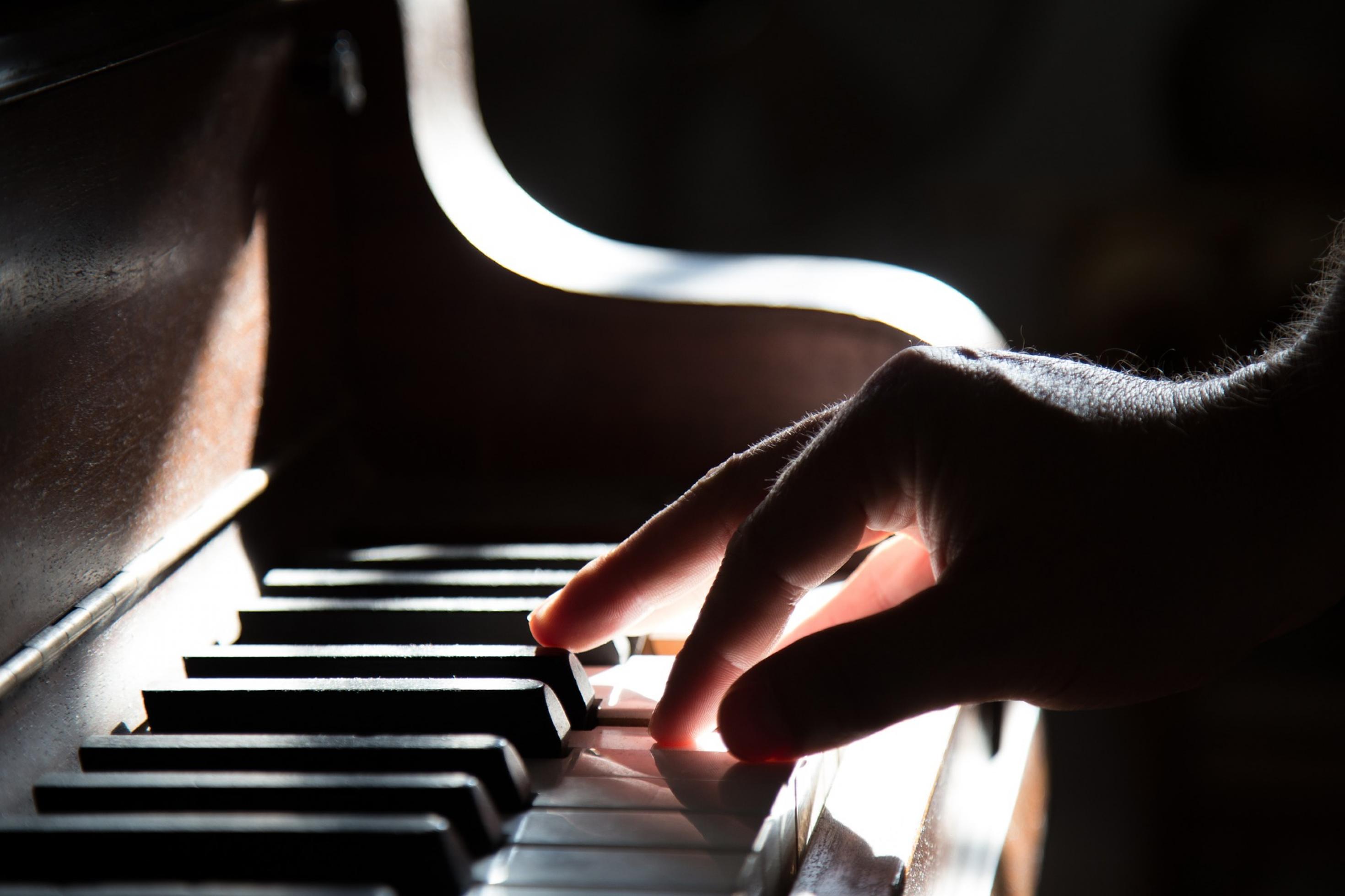 Die Hand eines Mannes spielt sanft die Tasten eine Klaviers.
