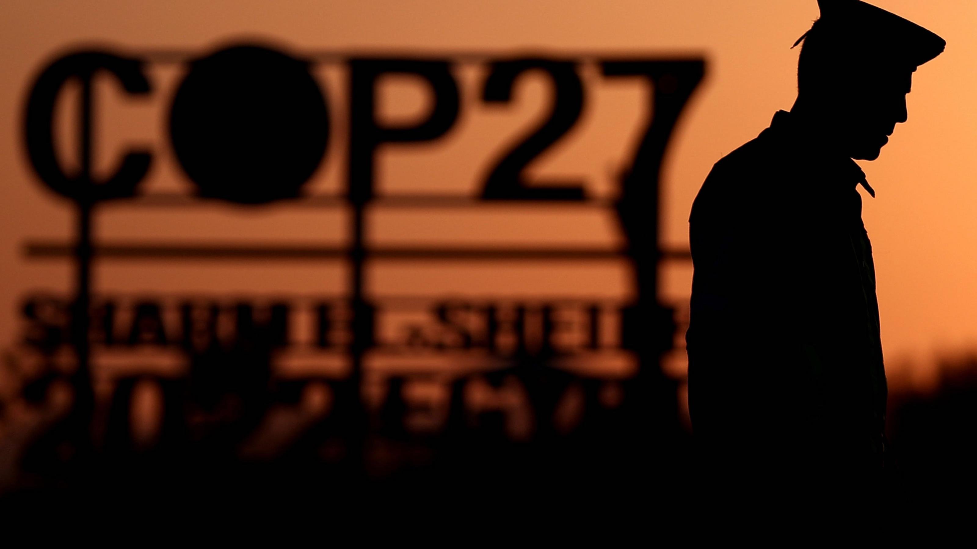 Silhouette eines Polizisten und eines Schriftzugs COP27 vor der untergehenden Sonne