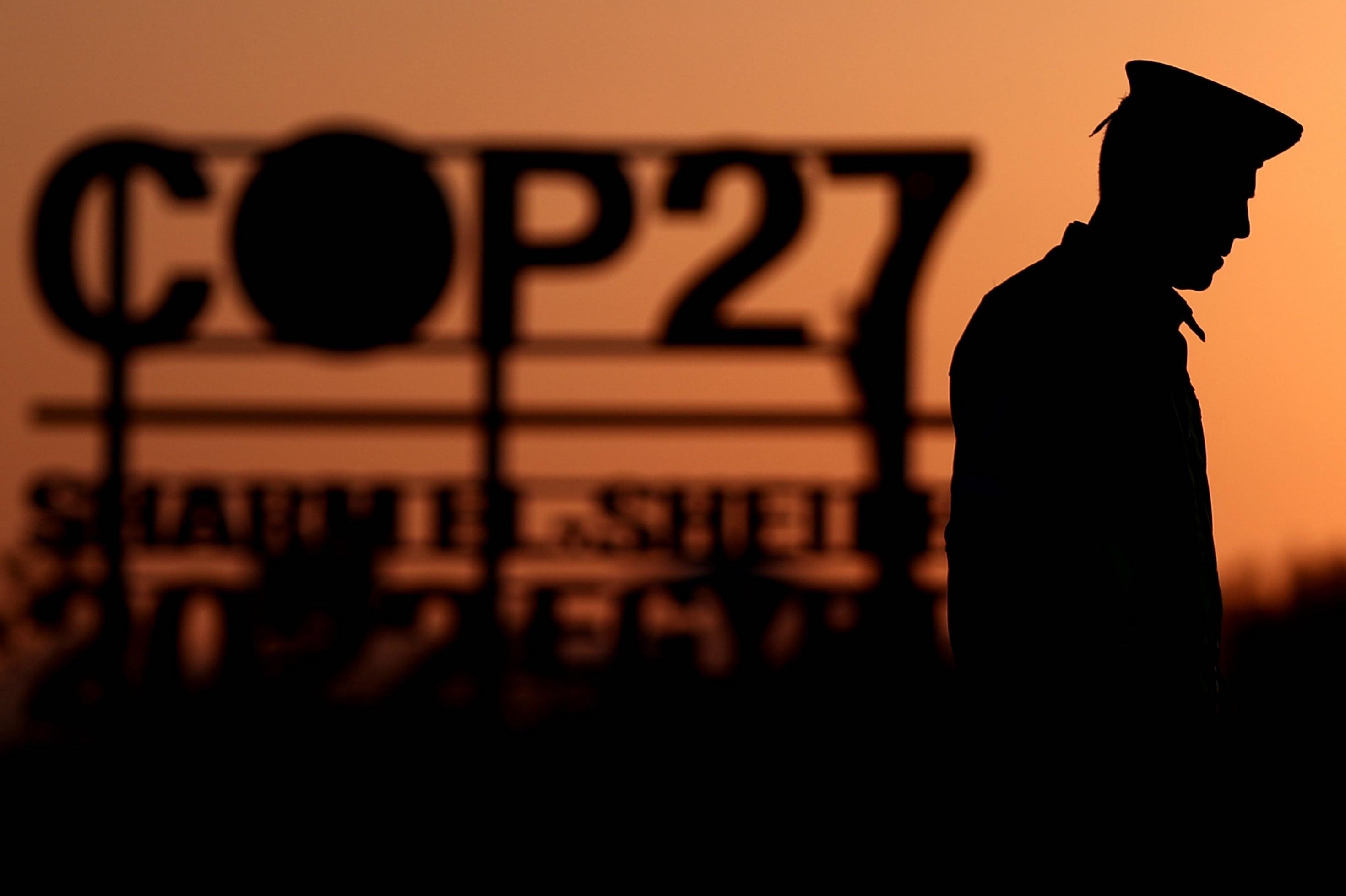 Silhouette eines Polizisten und eines Schriftzugs COP27 vor der untergehenden Sonne