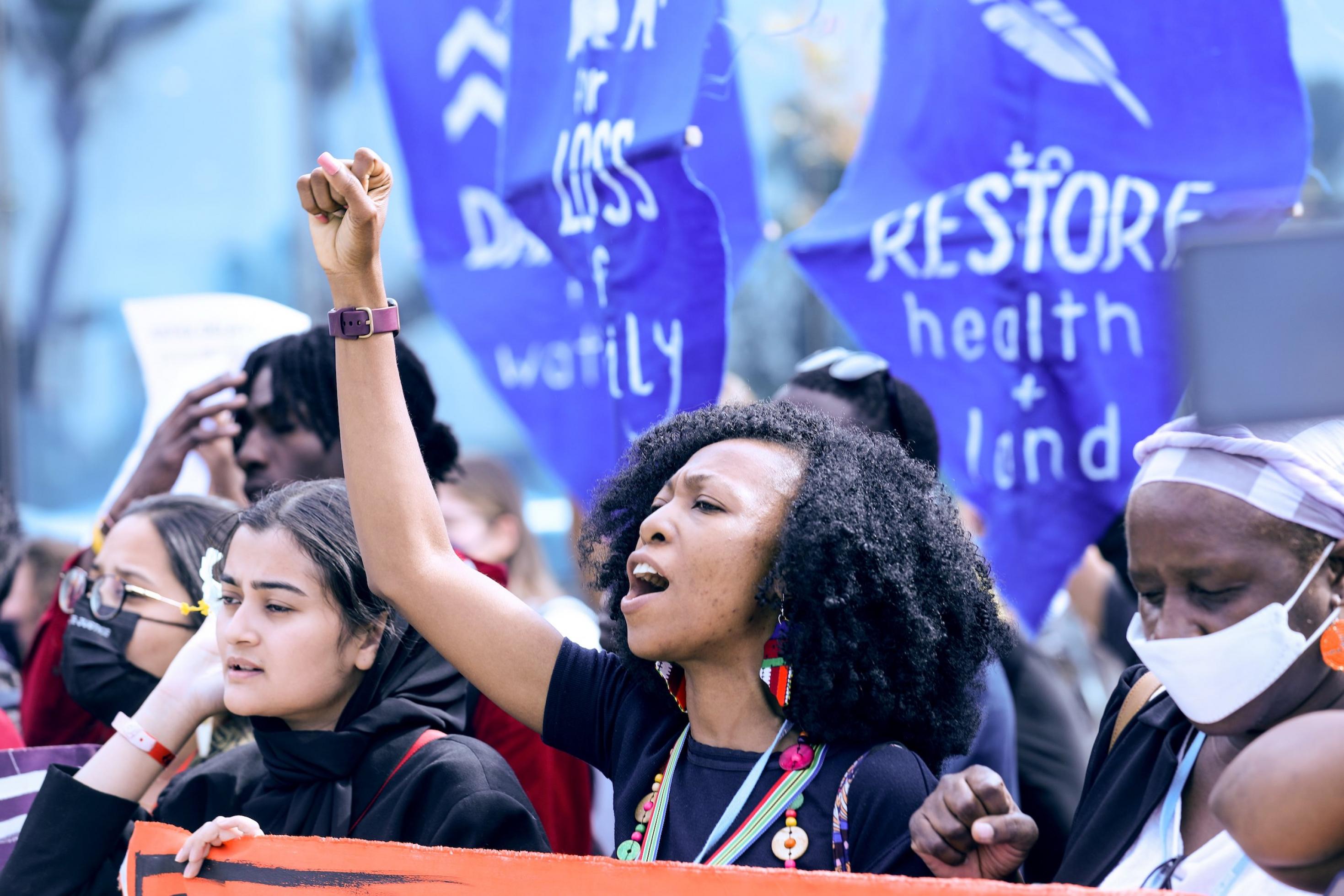 Demonstranten mit Schild „Restore Health and Land“.