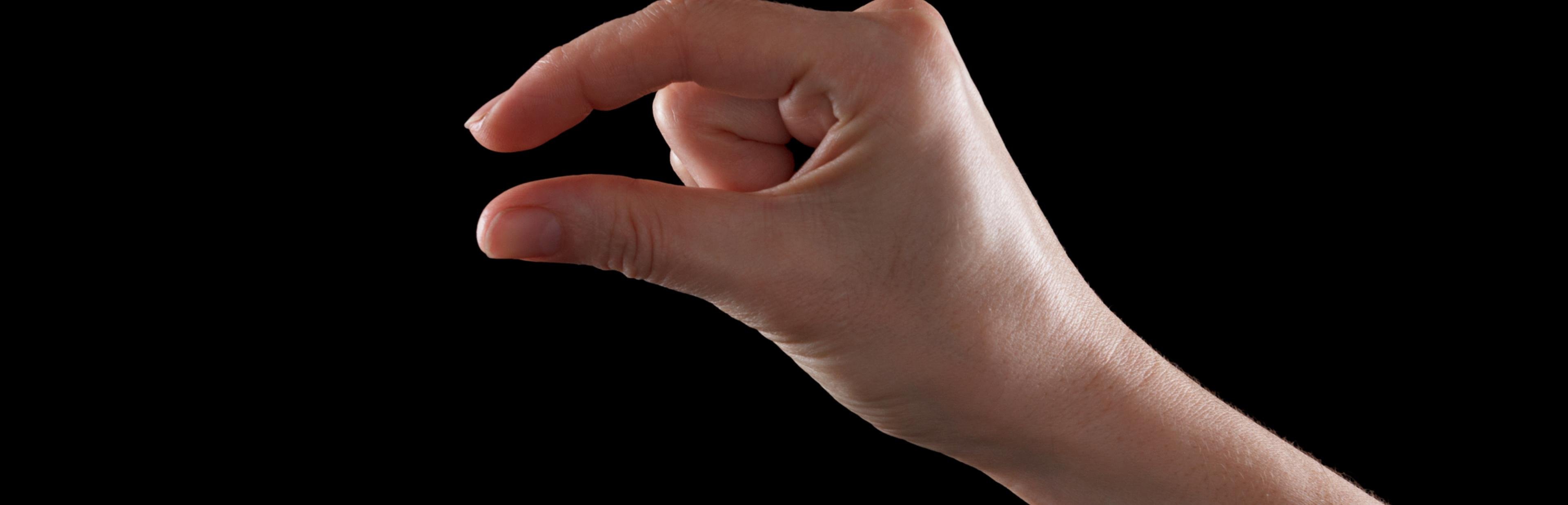 Eine Frauenhand hält die Finger nahe zusammen, um „klein“ zu signalisieren.