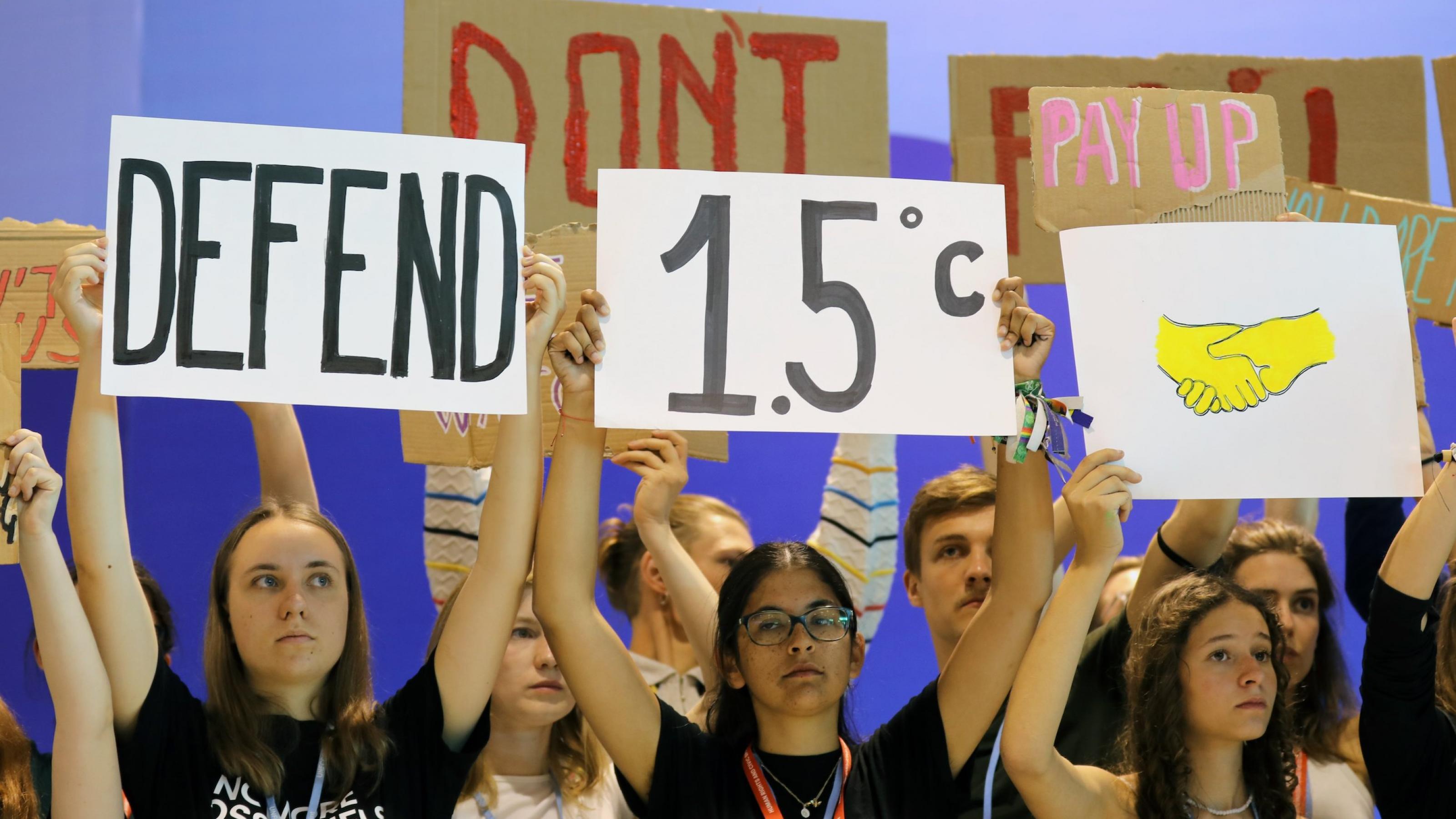 Junge Menschen halten ein Schild mit der Aufschrift „Defend 1,5 Grad“ in die Höhe.