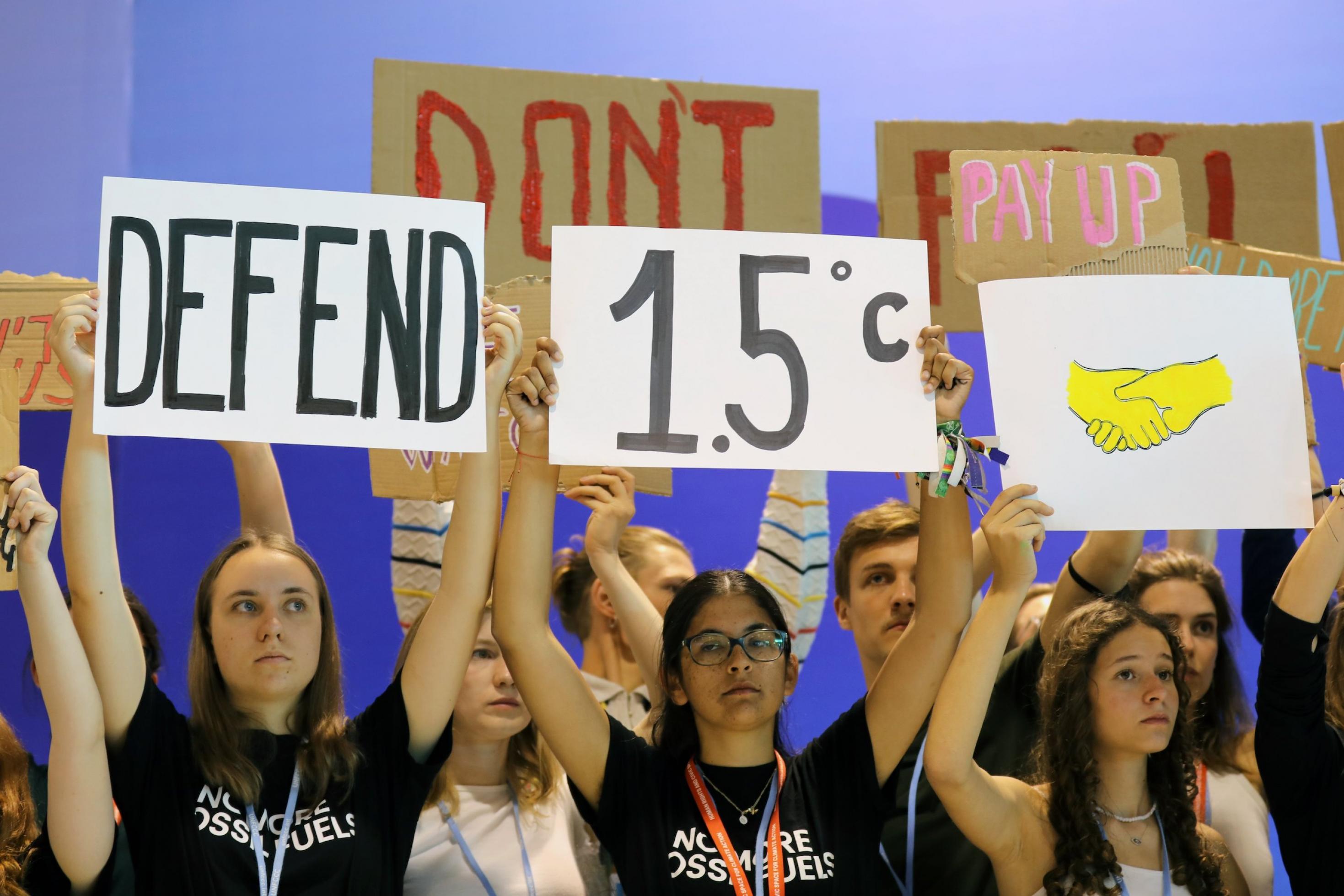 Junge Menschen halten ein Schild mit der Aufschrift „Defend 1,5 Grad“ in die Höhe.