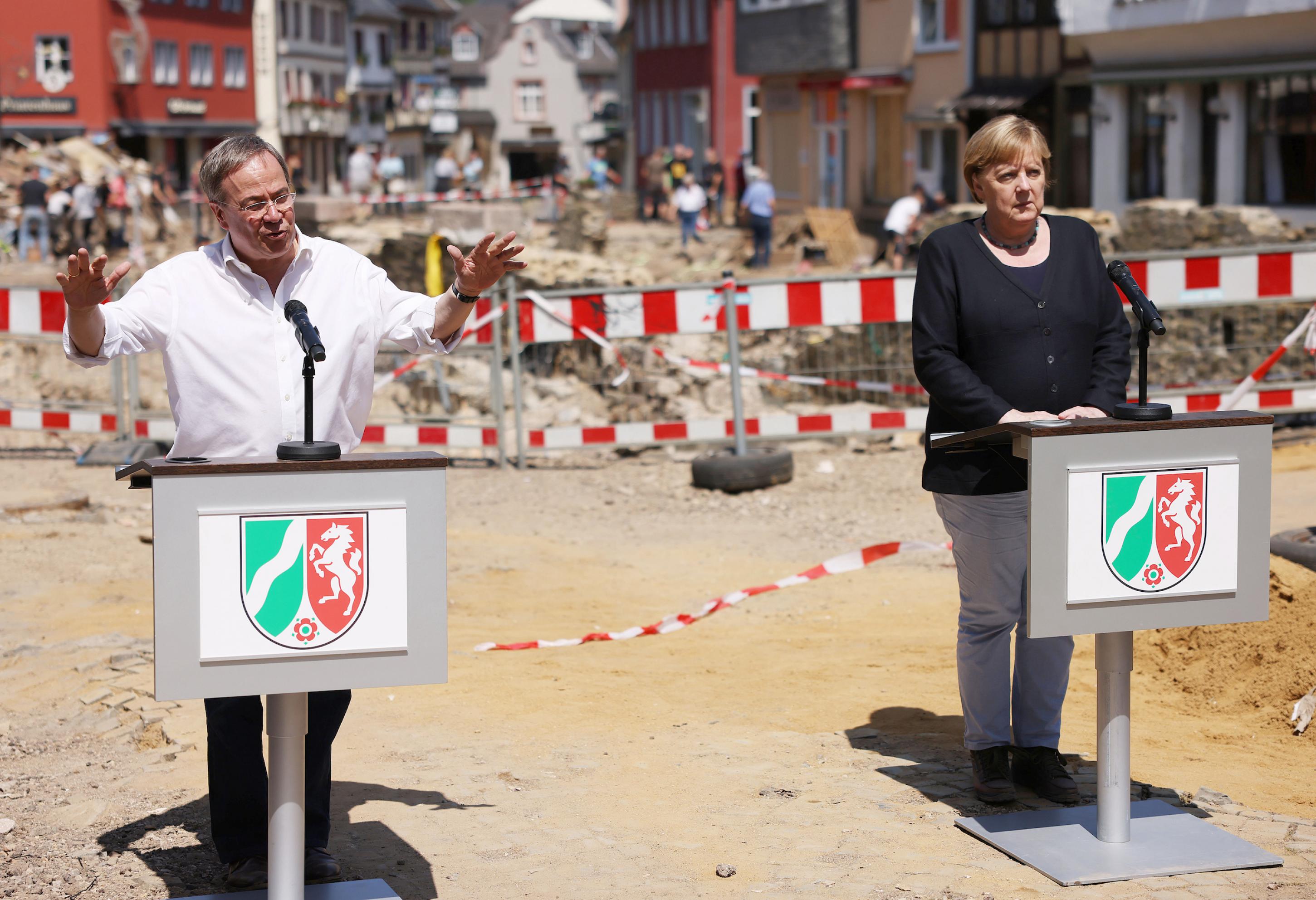 Armin Laschet (CDU), Ministerpräsident von Nordrhein-Westfalen, und Bundeskanzlerin Angela Merkel (CDU) geben eine Pressekonferenz in Bad Münstereifel vor Trümmern.
