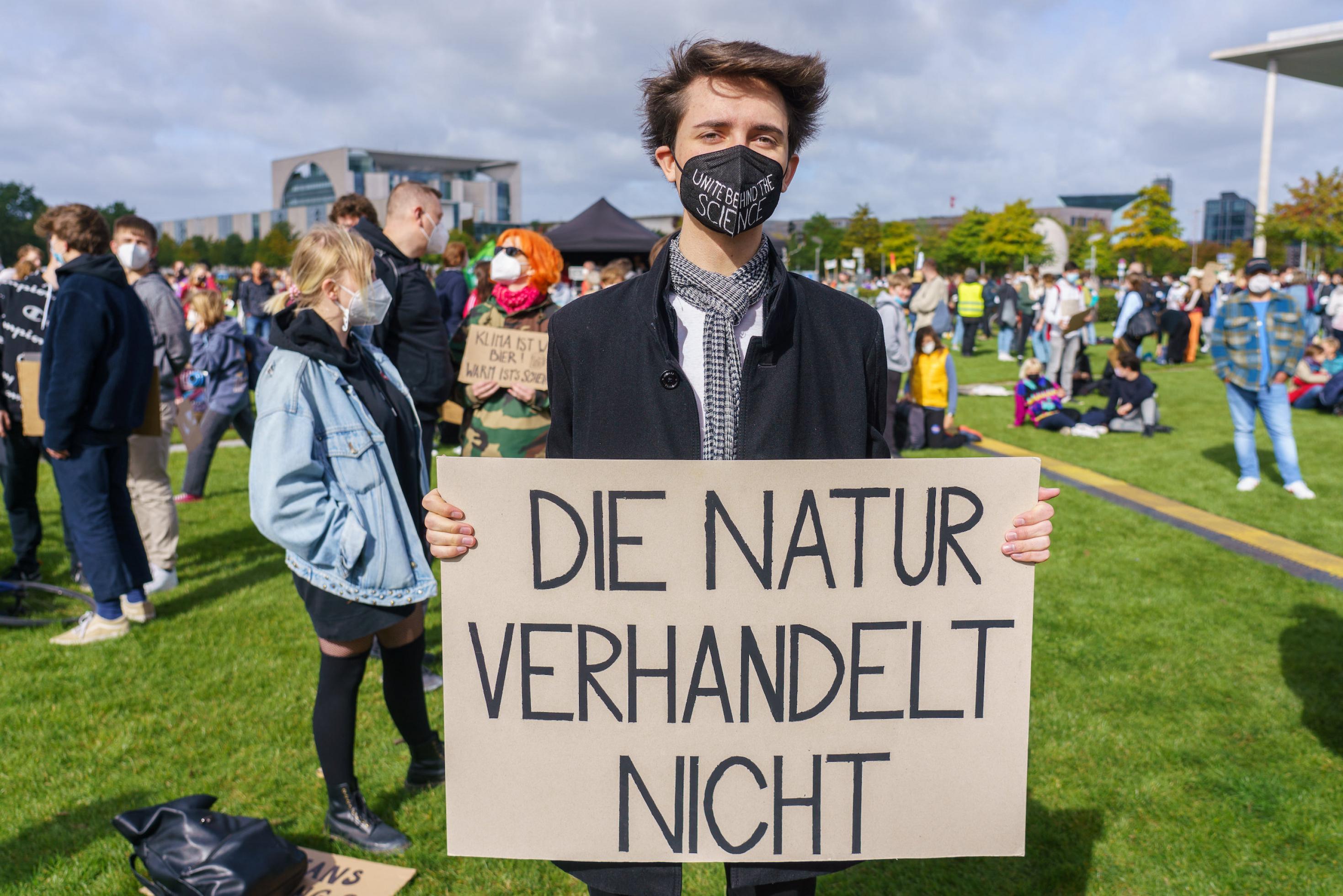Junger Mann bei einer Demonstration mit Schild „Die Natur verhandelt nicht“.