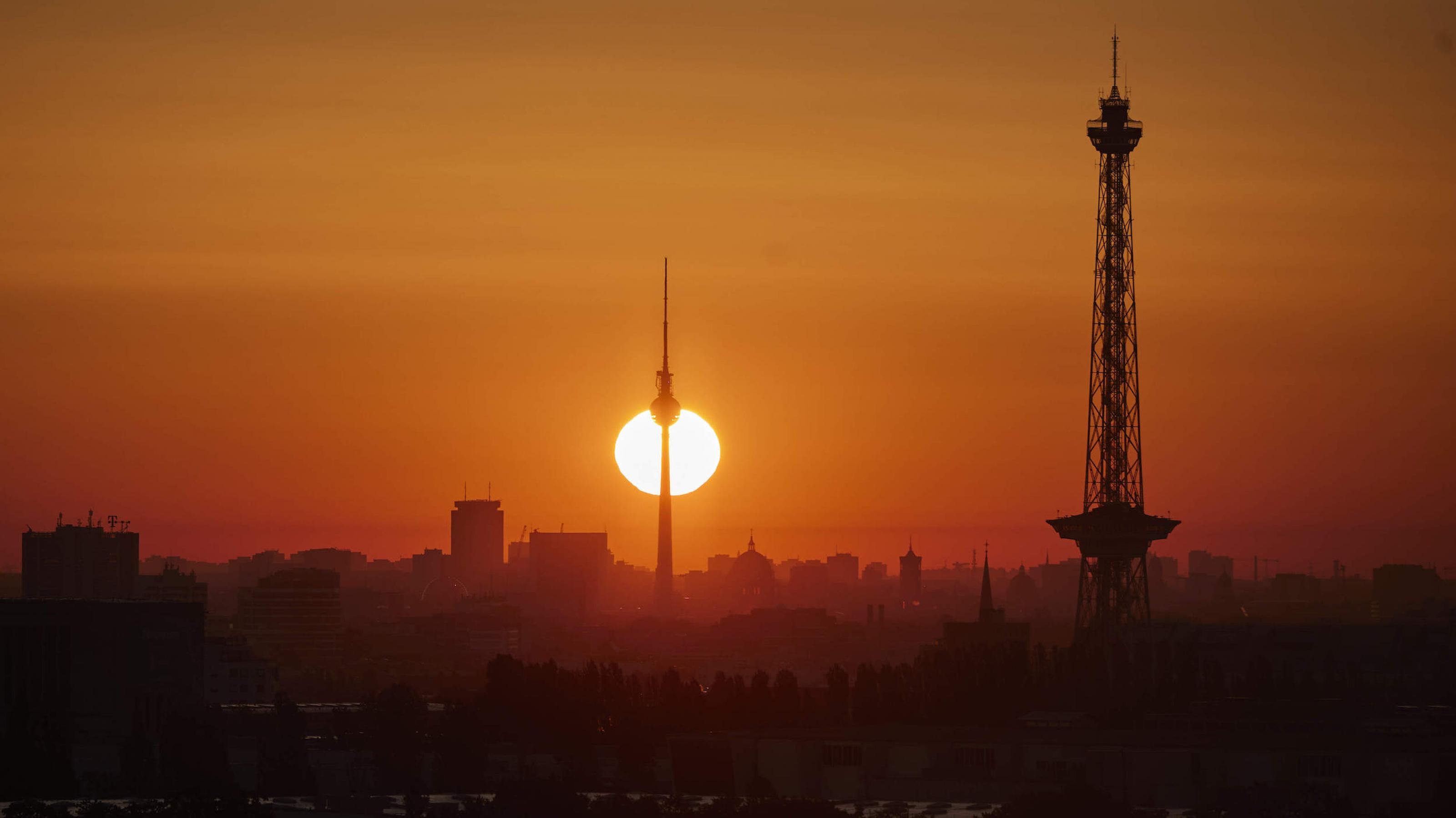 Blick auf den Sonnenaufgang von Westen aus. In der Ferne sind der Fernsehturm und der Funkturm zu sehen.