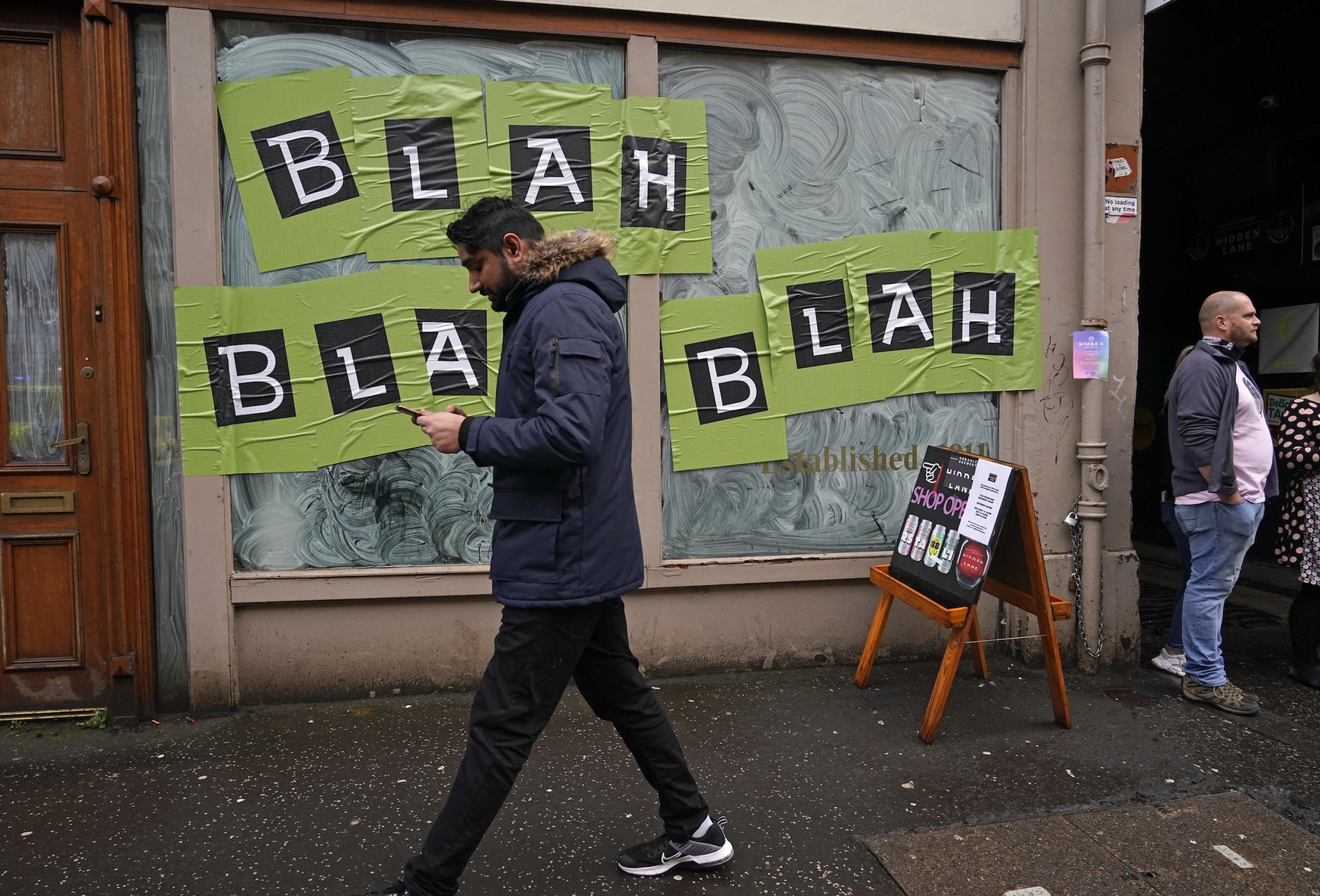 Plakate mit der Aufschrift „bla-bla-bla“ kleben auf einem Schaufenster in Glasgow.
