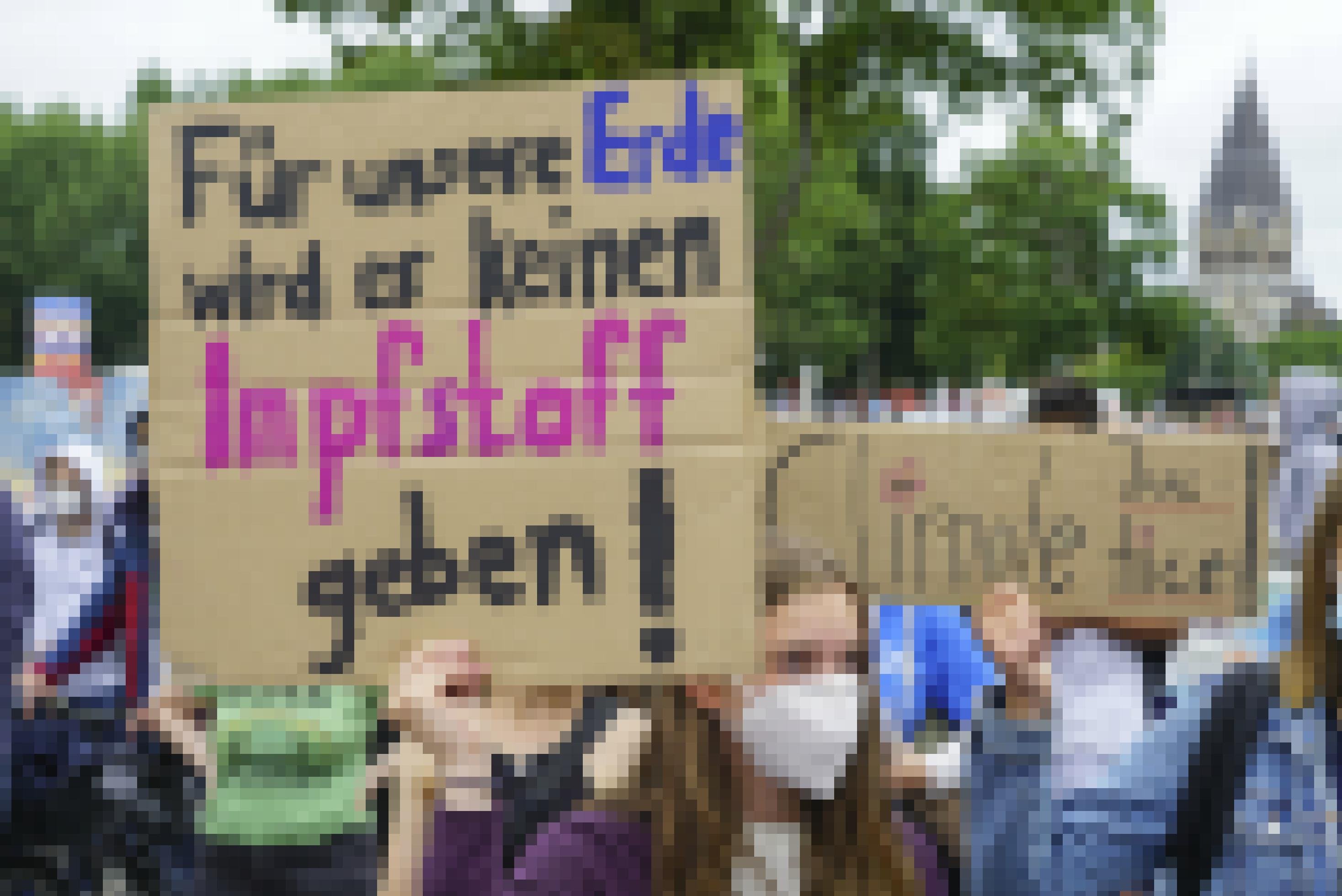 Eine junge Frau hält bei der Demonstration ein handgeschriebenes Schild hoch, auf dem steht: „Für unsere Erde gibt es keinen Impfstoff.“