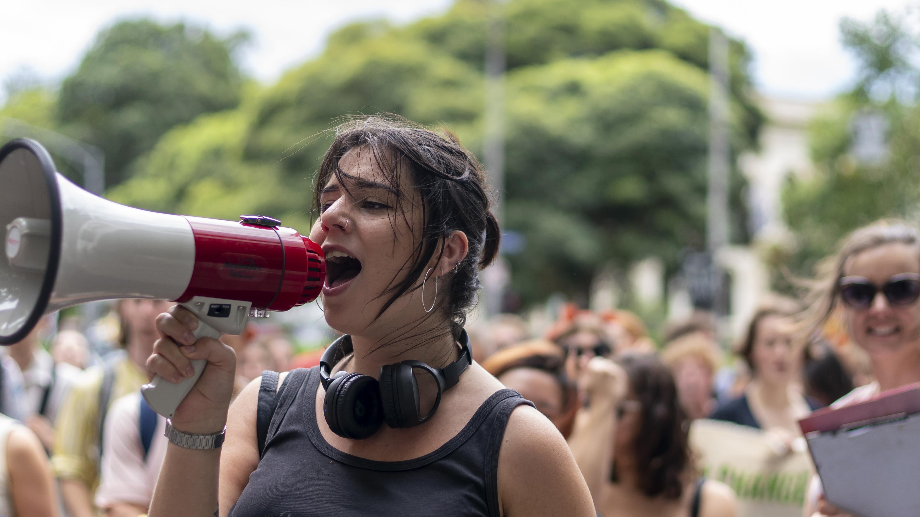 Eine junge Frau steht mit einem Megafon vor einer Gruppe Protestierender der Fridays-for-Future-Bewegung
