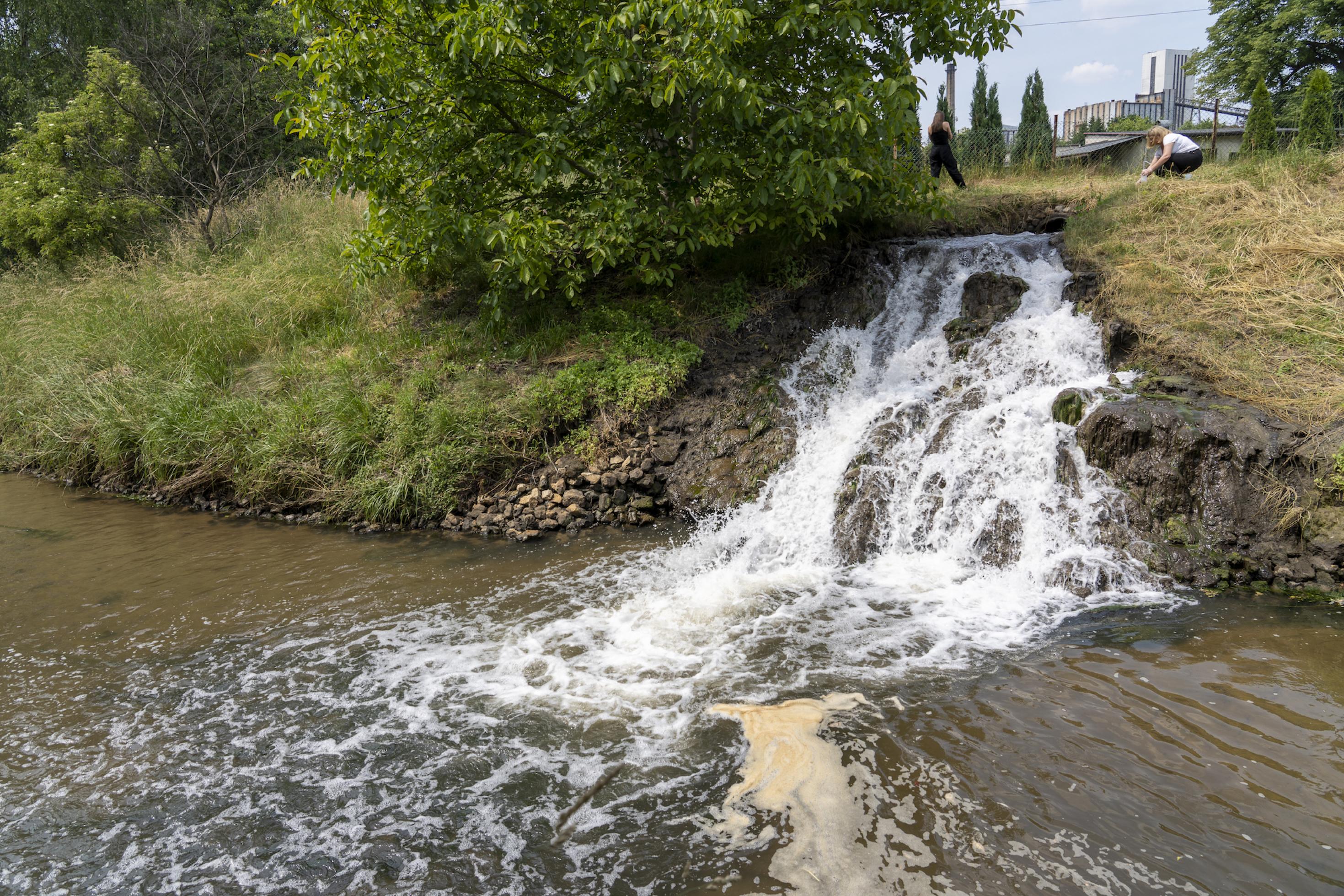 Foto von Wasser, das Wasserfallähnlich in einen Fluss läuft.