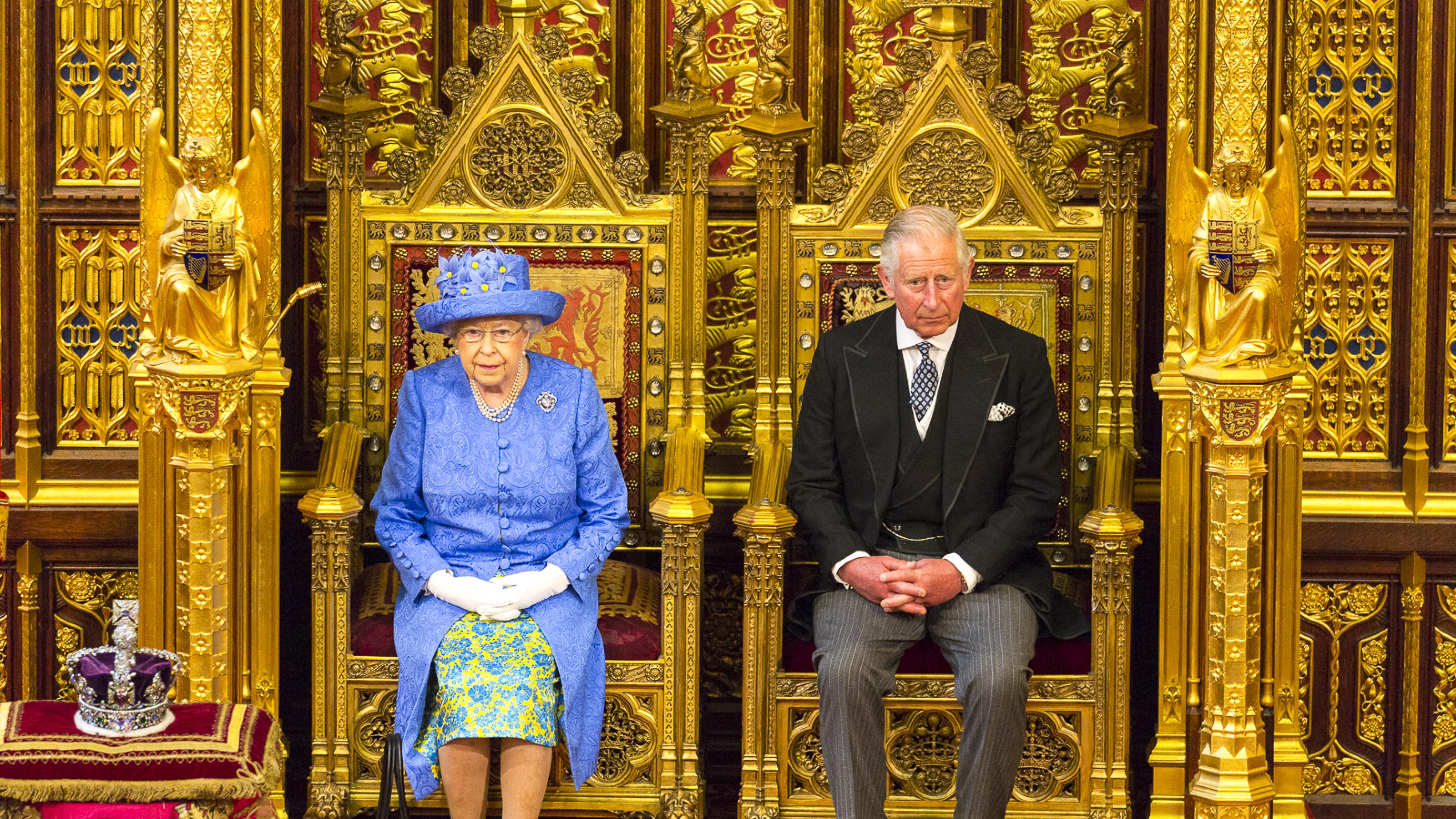 Königin Elisabeth II. und Prinz Charles sitzen nebeneinander auf ihren Thronen.
