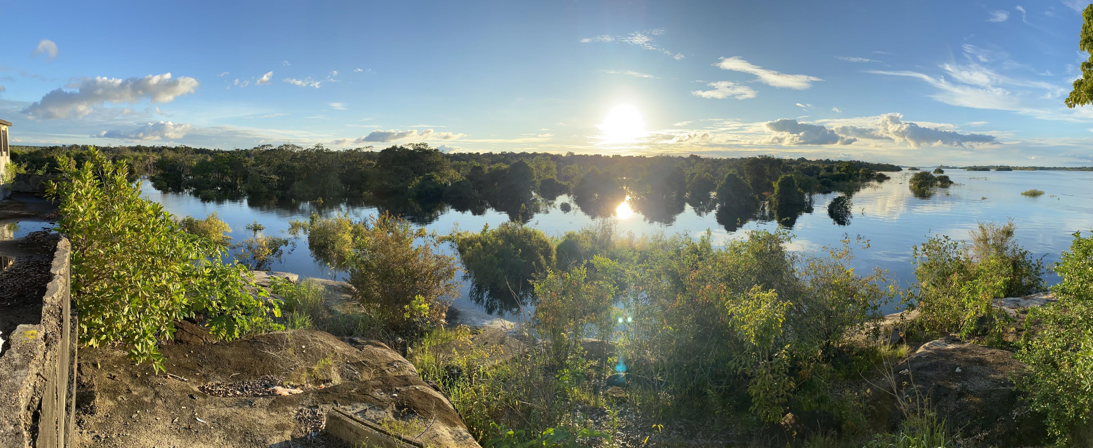 Bäume und die Überreste einer Ruine spiegeln sich im Flusswasser.