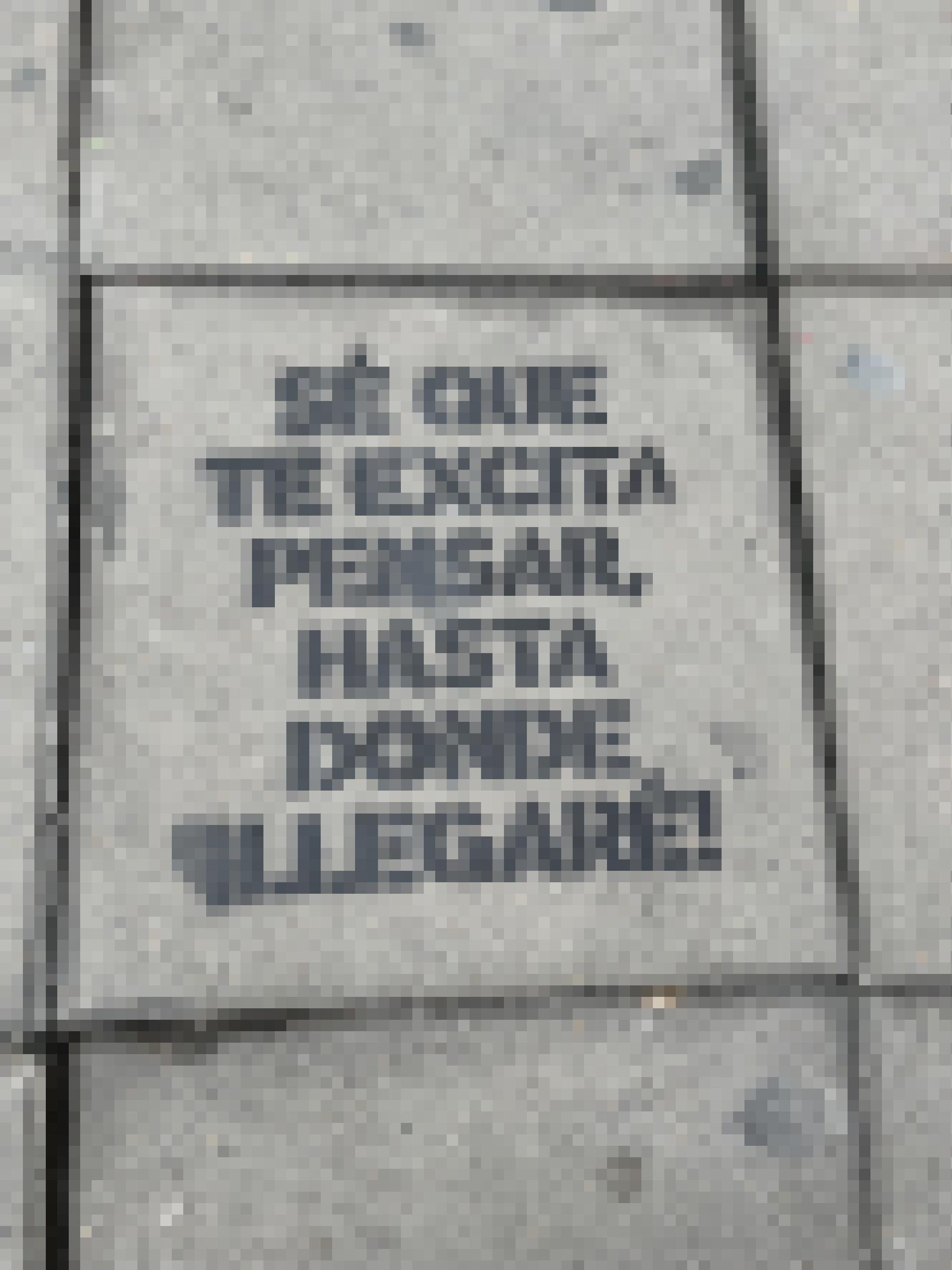 Die Textzeile steht auf Spanisch gesprüht auf einer grauen Bodenplatte auf dem Gehweg.