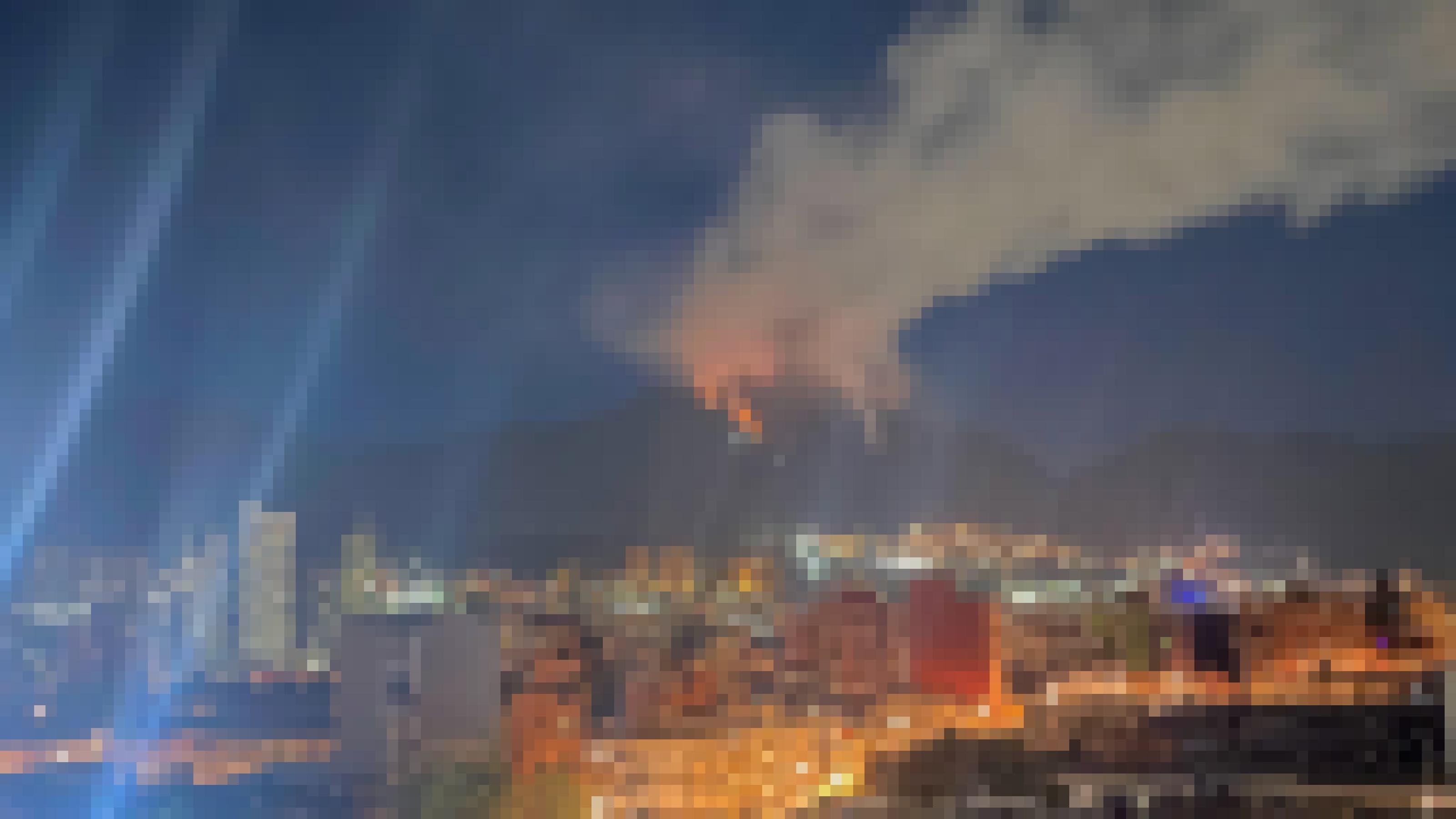 Stadtpanorama Bogotá bei Nacht mit Hochhäusern. Im Hintergrund ein Gebirge mit einem Gipfel, von dem Rauch aufsteigt. Eine glühende Rinne zieht sich schräg die Hälfte des Bergs hinab.