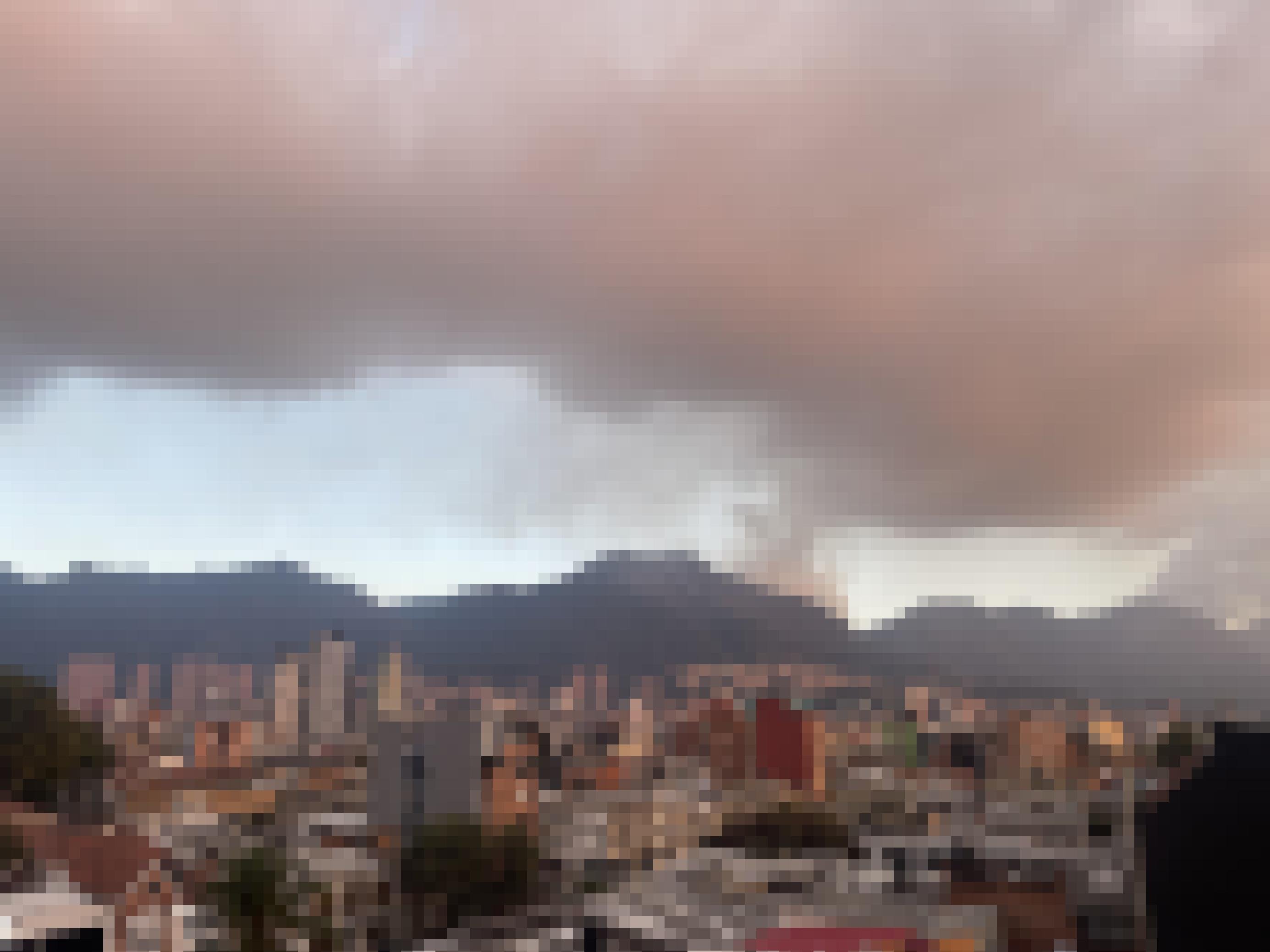 Stadtpanorama von Bogotá mit Hochhäusern. Im Hintergrund eine Gebirgskette. Von einem Gipfel steigt Rauch. Der zieht sich horizontal komplett übers Bild. Zwischen Bergkette und Rauchkette ist nur ein schmaler hellblauer Streifen Himmel zu sehen.