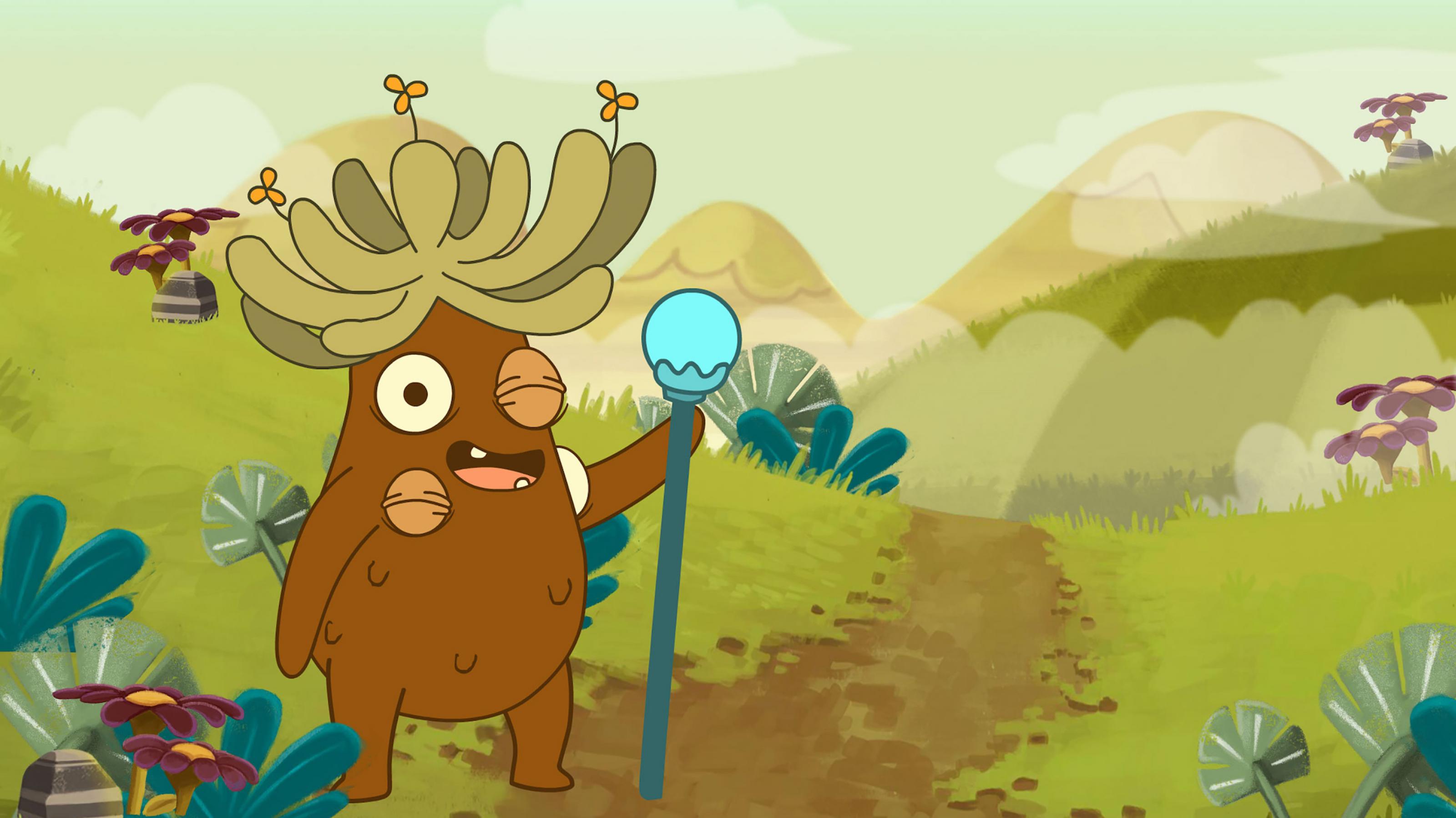 Eine Kartoffel-artige Zeichentrickfigur mit fünf Augen (davon vier im Bild, zwei sind zugedrückt) steht in Berglandschaft. Sie hat eine Art grüne Rastalockenkrone auf dem Kopf, aus der Blümchen ragen. In einer Hand hält sie ein Szepter.