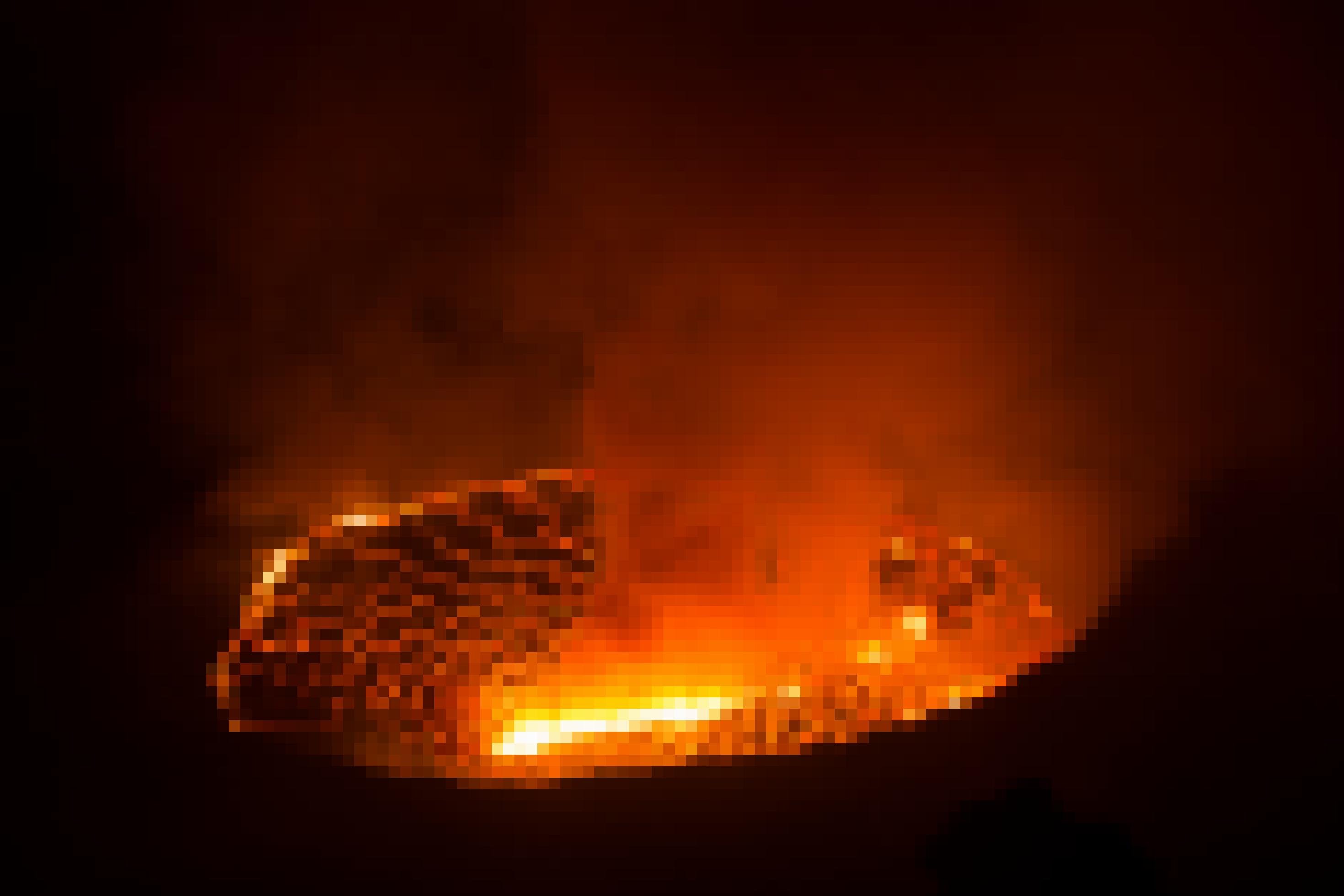 Der Nachthimmel über dem Krater des Vulkans Nyiragongo ist rot gefärbt, durch den Feuerschein, der von dem Lavasee aufsteigt. Der Lavasee sieht wie eine Landkarte aus, weil durch erkaltete, schwarzer Lava rote Streifen noch glühender Lava ziehen wie Adern.