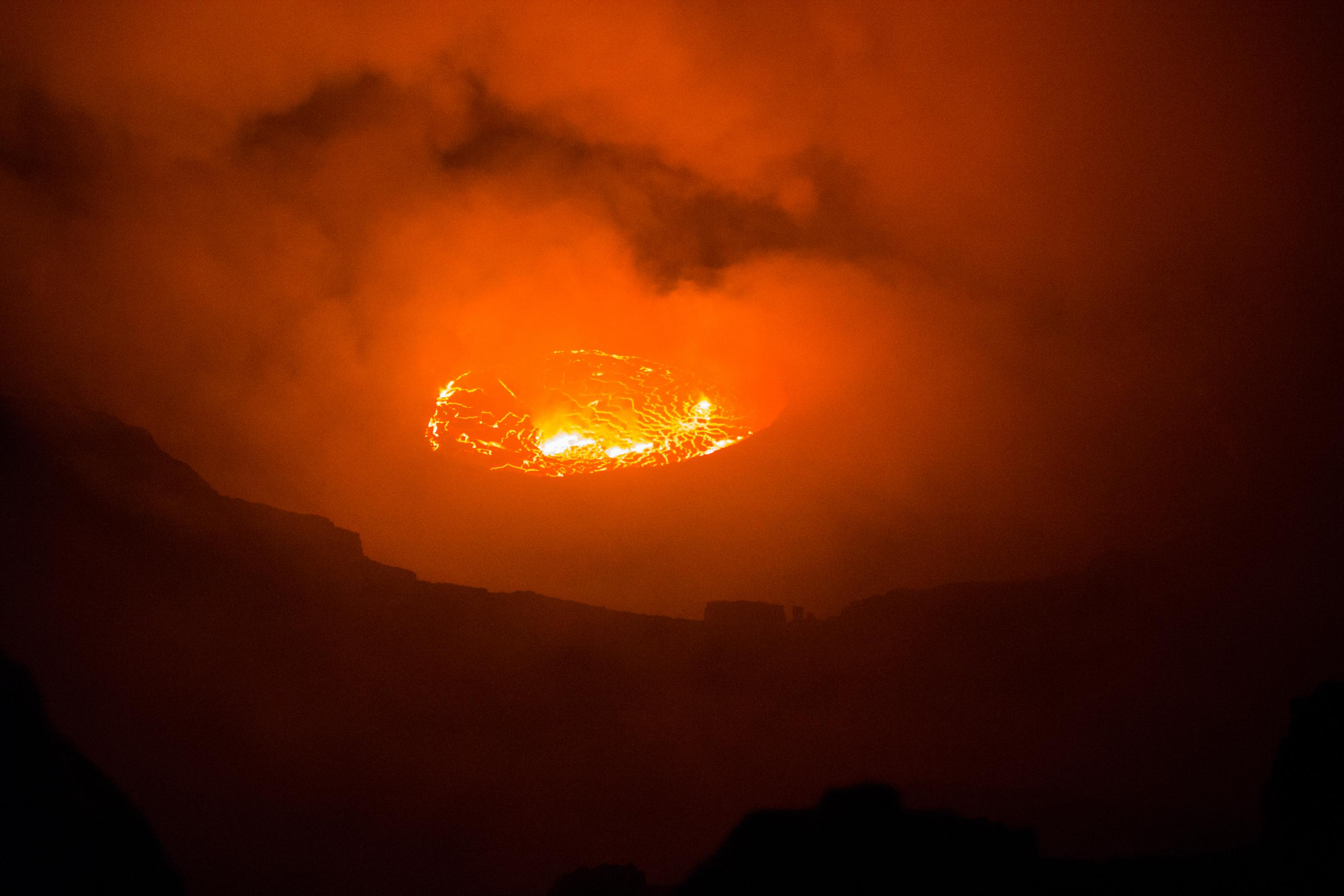 Der Lavasee des Nyiragong ist immer zu sehen, nicht nur beim Ausbruch. Der Vulkan kann in normalen Zeiten bestiegen werden, vom Kraterrand guckt man hinunter auf die Lava. Nachts färbt der Feuerschein die Wolken rot.