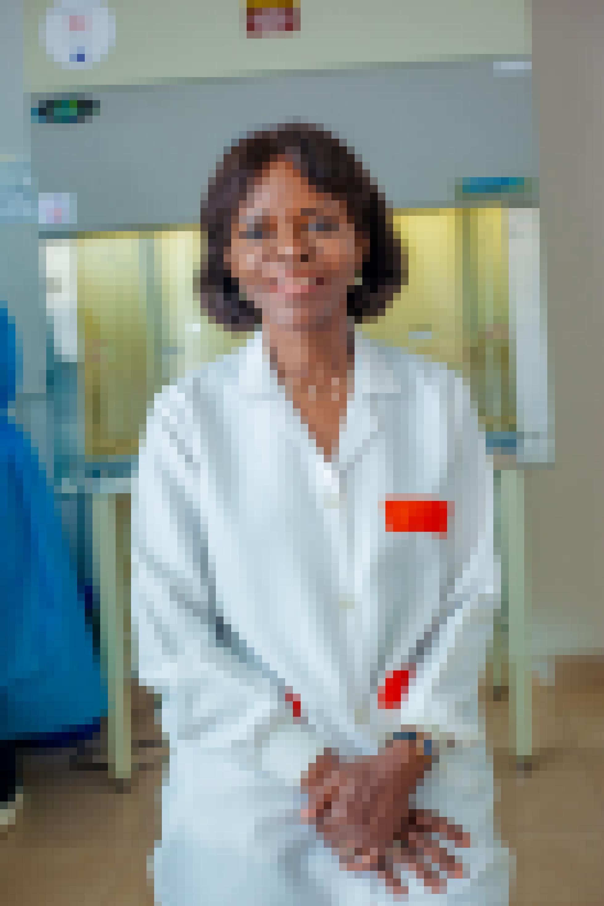 Francine Ntoumi, eine Frau Anfang 60, blickt lächelnd in die Kamera. Sie ist in ihrem Labor, trägt einen weißen Kittel.