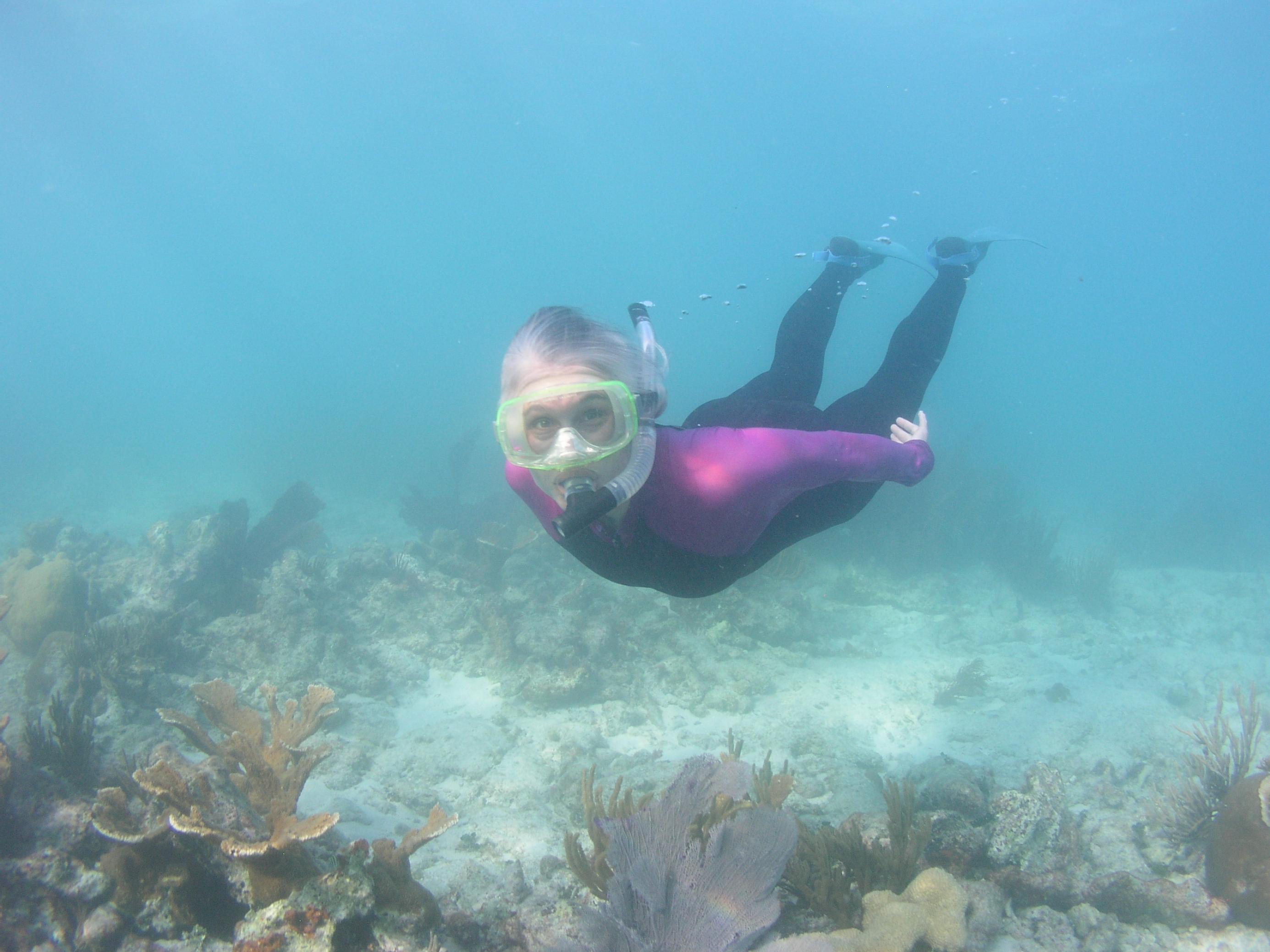 Die Wissenschaftlerin schnorchelt in türkisblauem Meer über lebendigen Korallen und sieht glücklich aus