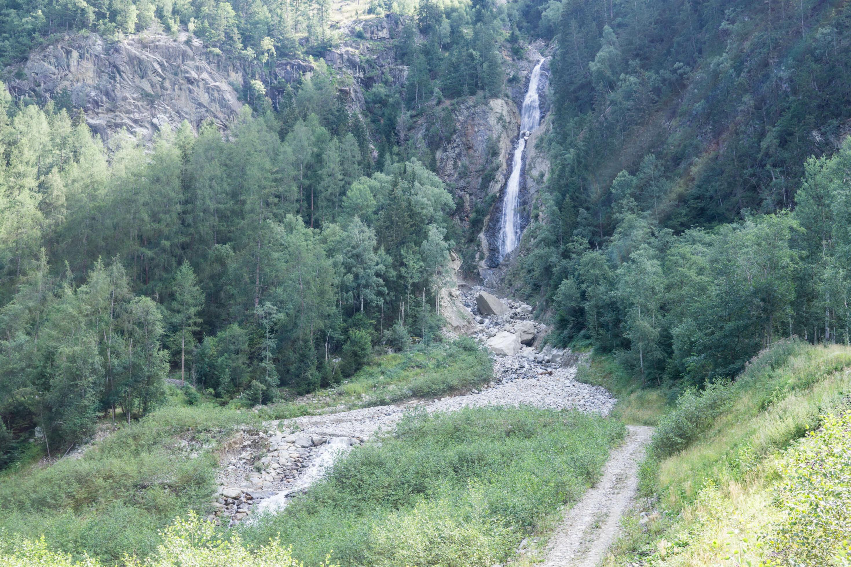 Felswand mit schmalem Wasserfall in Gebirgslandschaft
