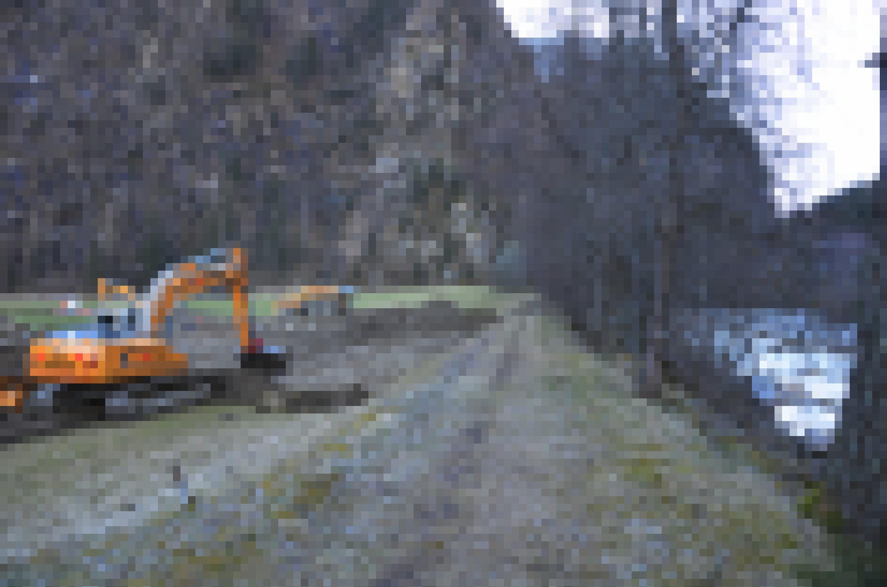 Ein Bagger am Ufer des Baches gräbt.