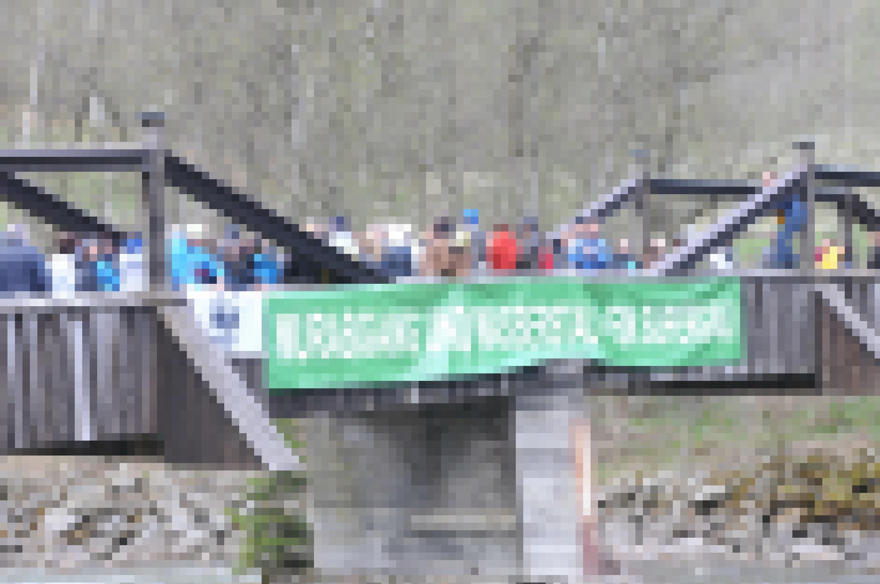 Demonstranten auf alter Holzbrücke, auf der ein grünes Transparent hängt mit dem Text: Murabgang und Wasserstand – ein Supergau!