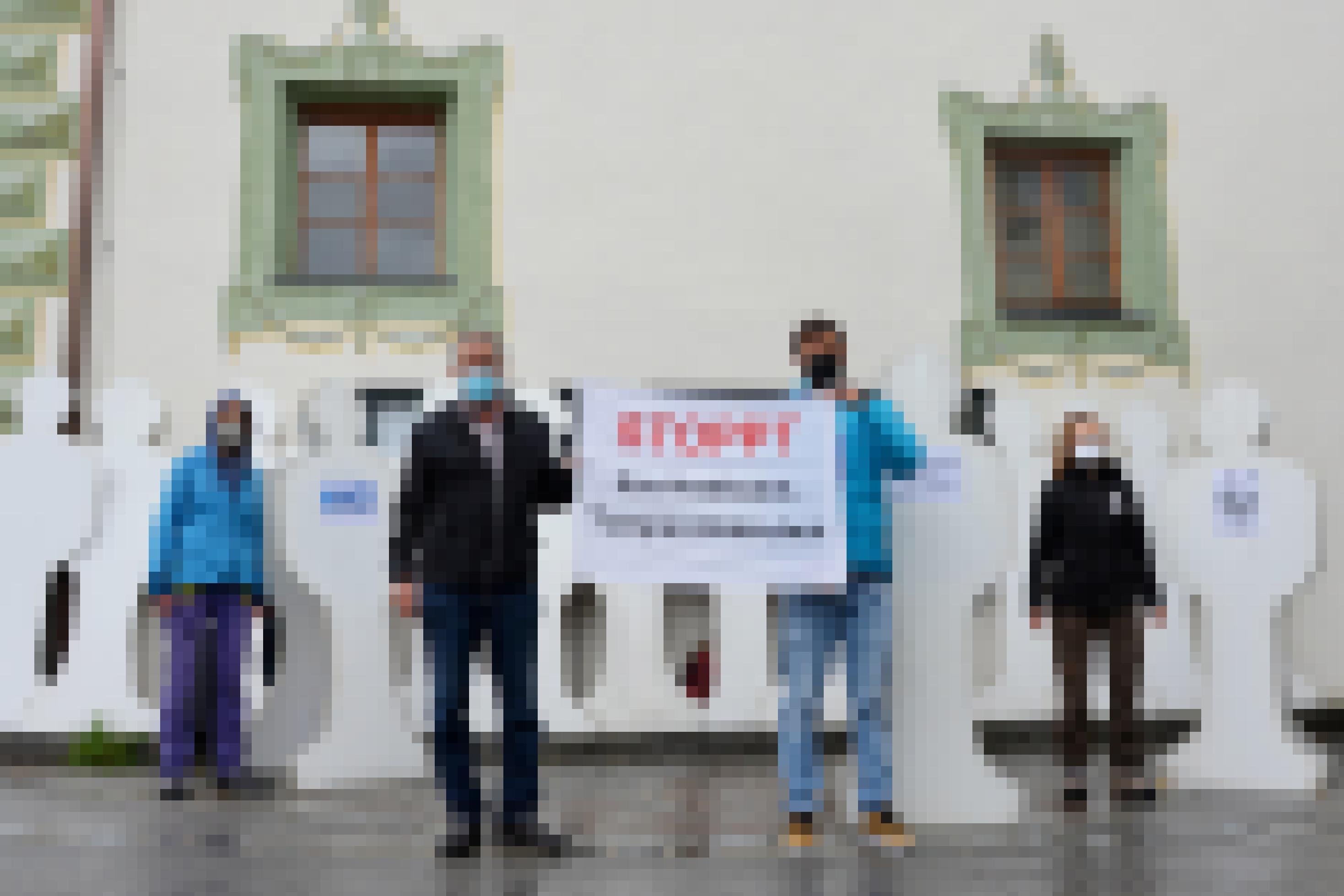 Protestierende mit Pappfiguren vor altem Gebäude.