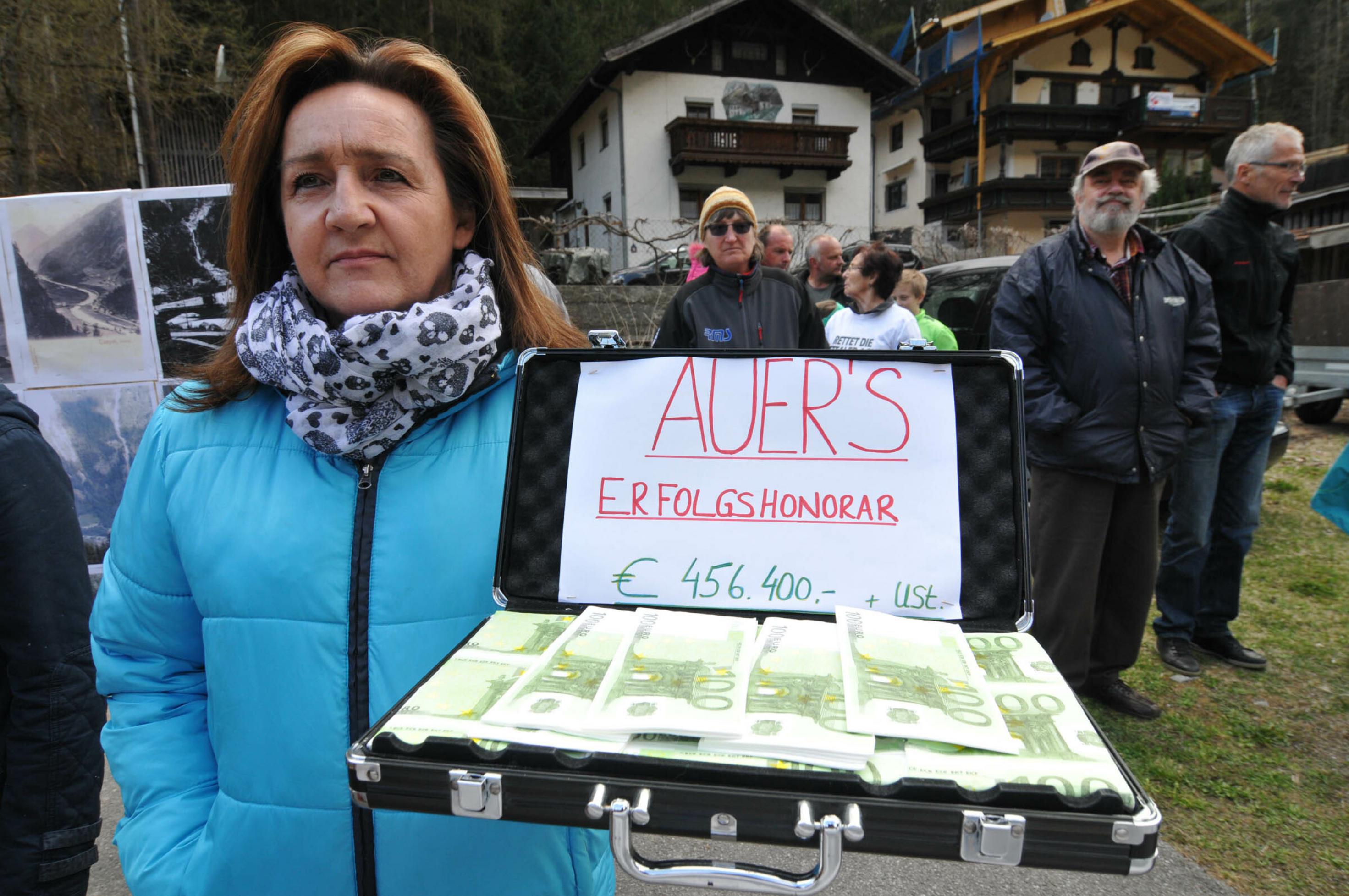 Frau mit Aktenkoffer mit Papiergel. Auf einem Zettel steht: Auers Erfolgshonorar € 456.400 + USt.