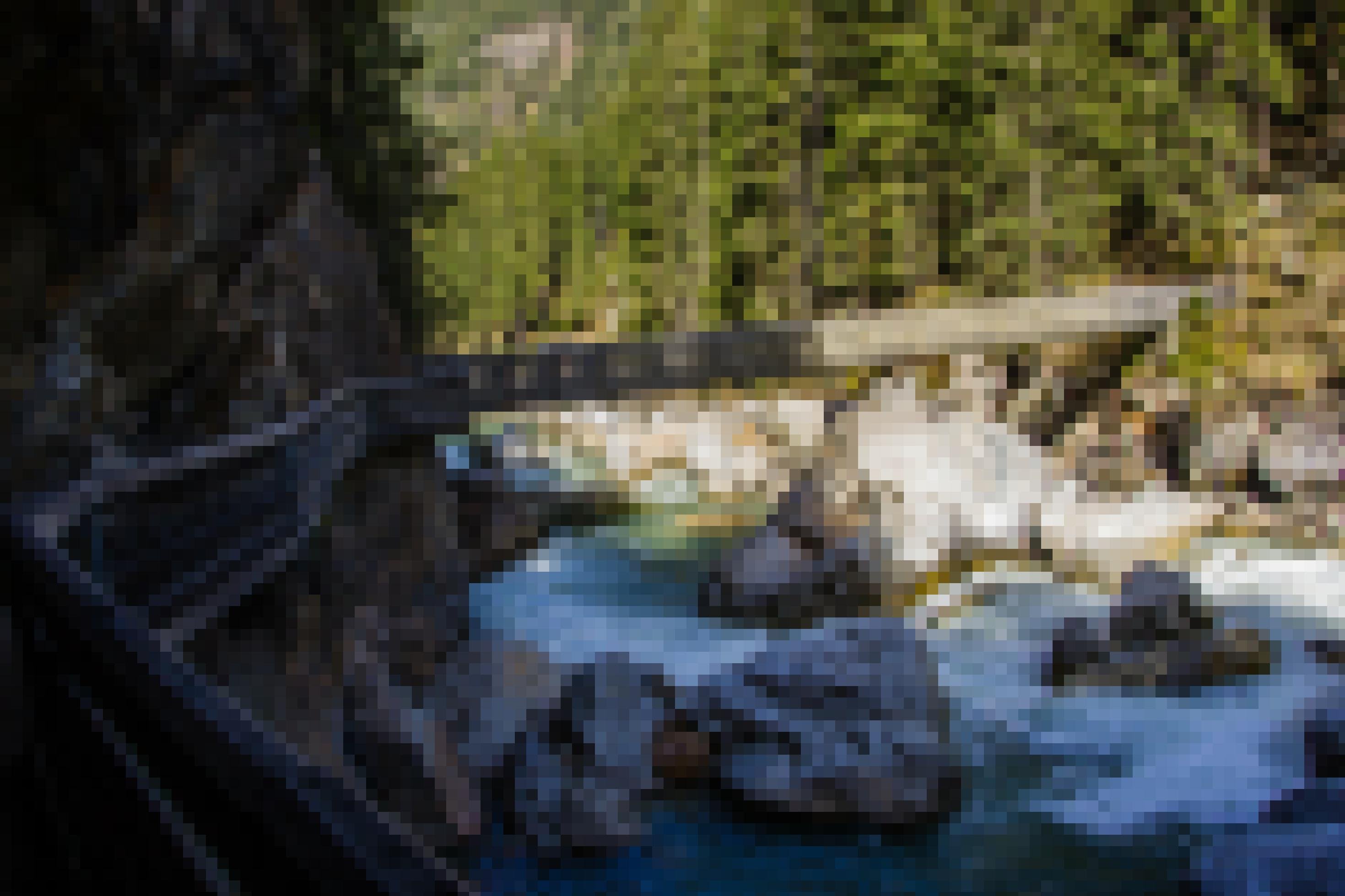 Wilder Gletscherbach mit großen Steinen und einer querenden Holzbrücke.