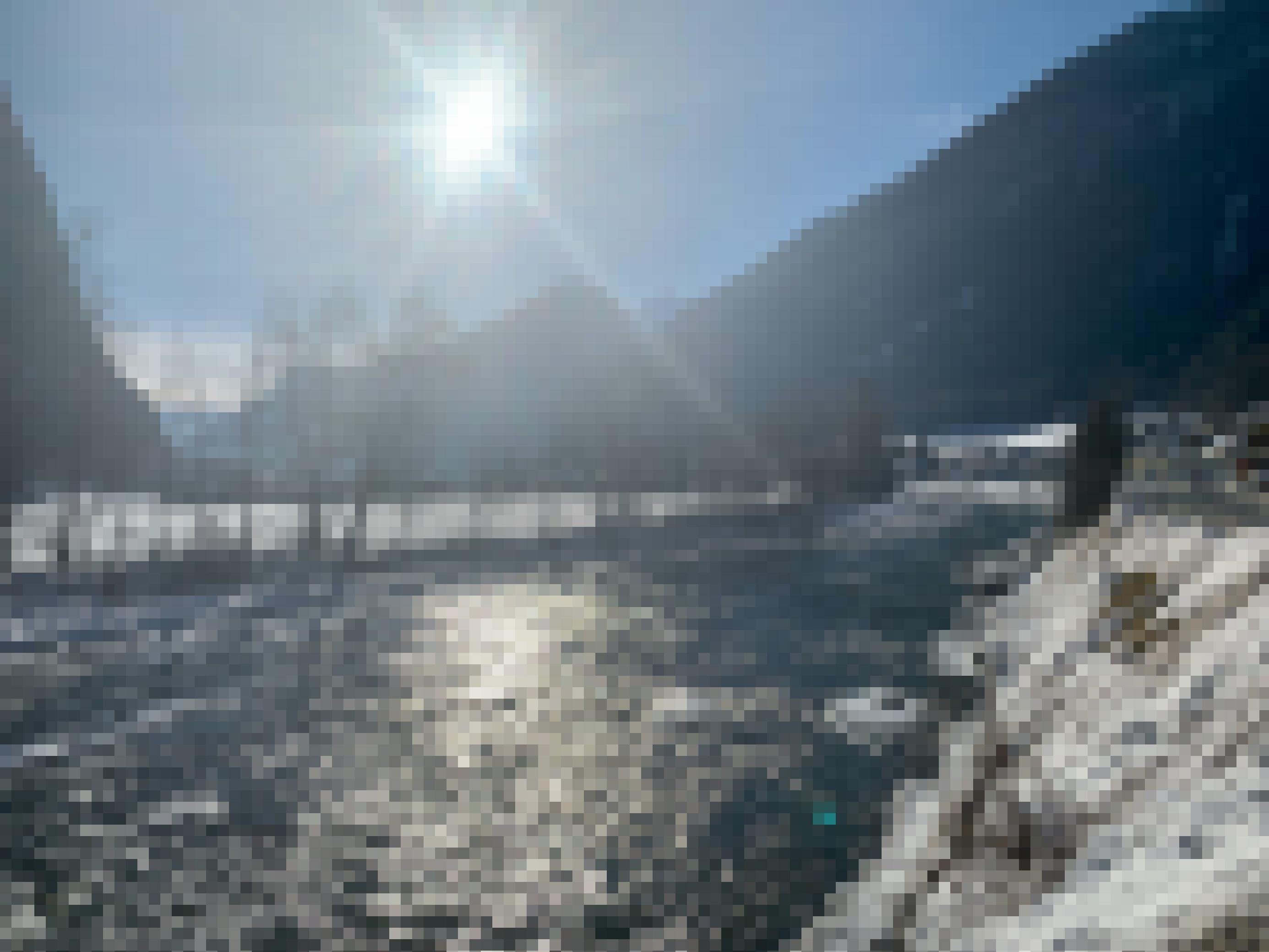 Gebirgsbach in einem Tal mit Schneelandschaft und blauem Himmel