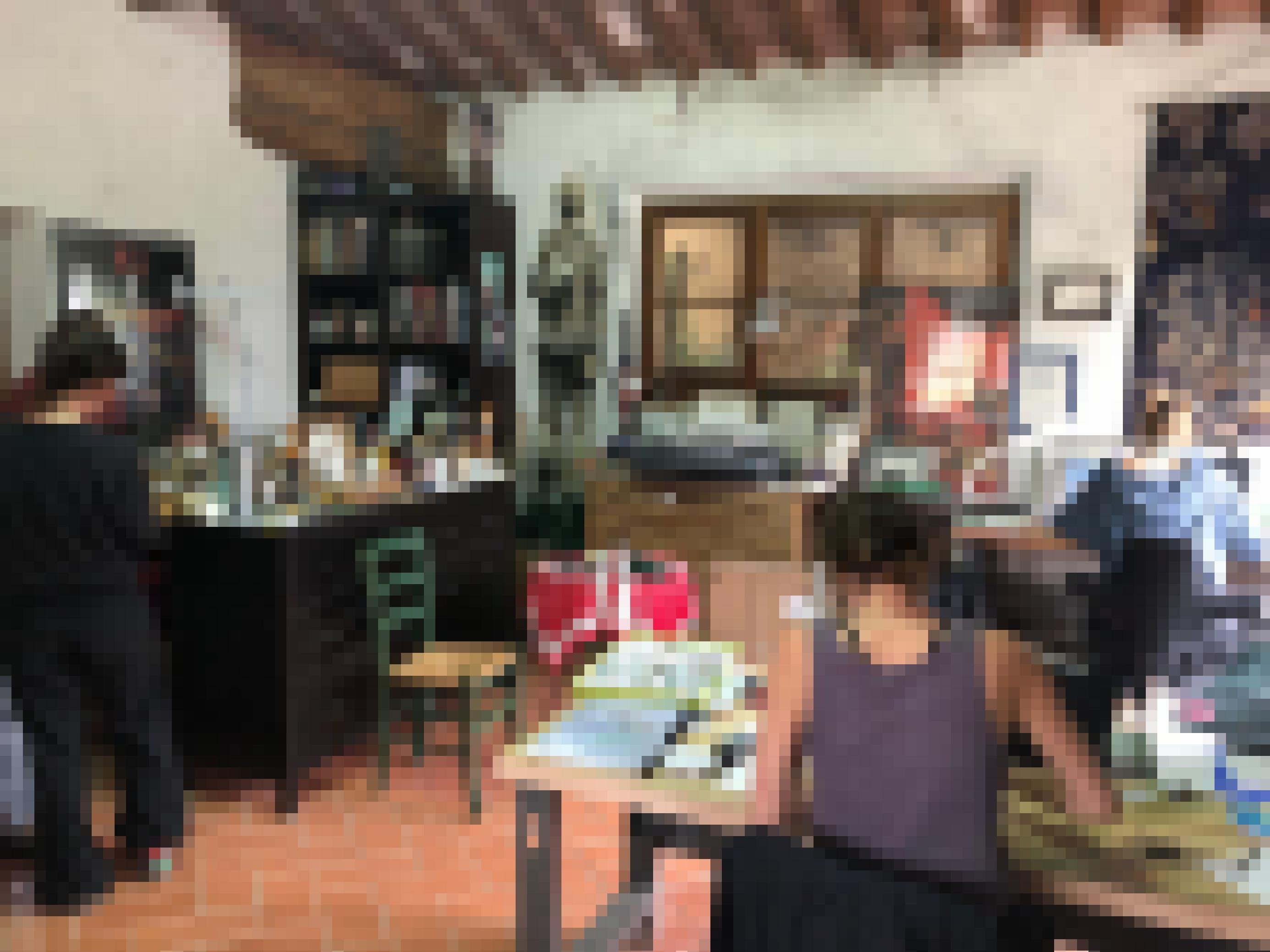 Ein Raum mit Holzdecke und Tonboden, vollgestellt mit Büchern, Tischen und Kunstmaterial. Drei junge Frauen arbeiten an den Tischen an ihren Illustrationen.