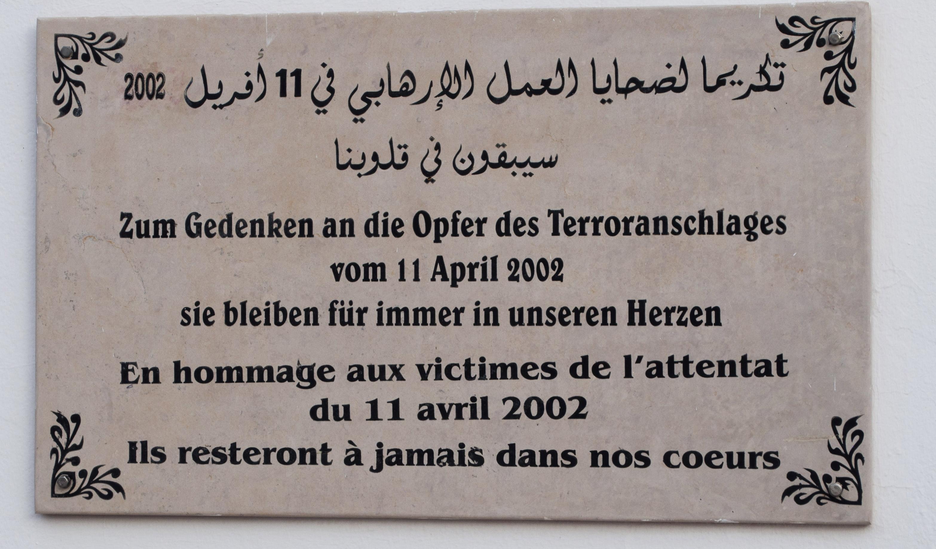 Gedenktafel in Marmor, auf der in drei Sprachen der Opfer gedacht wird