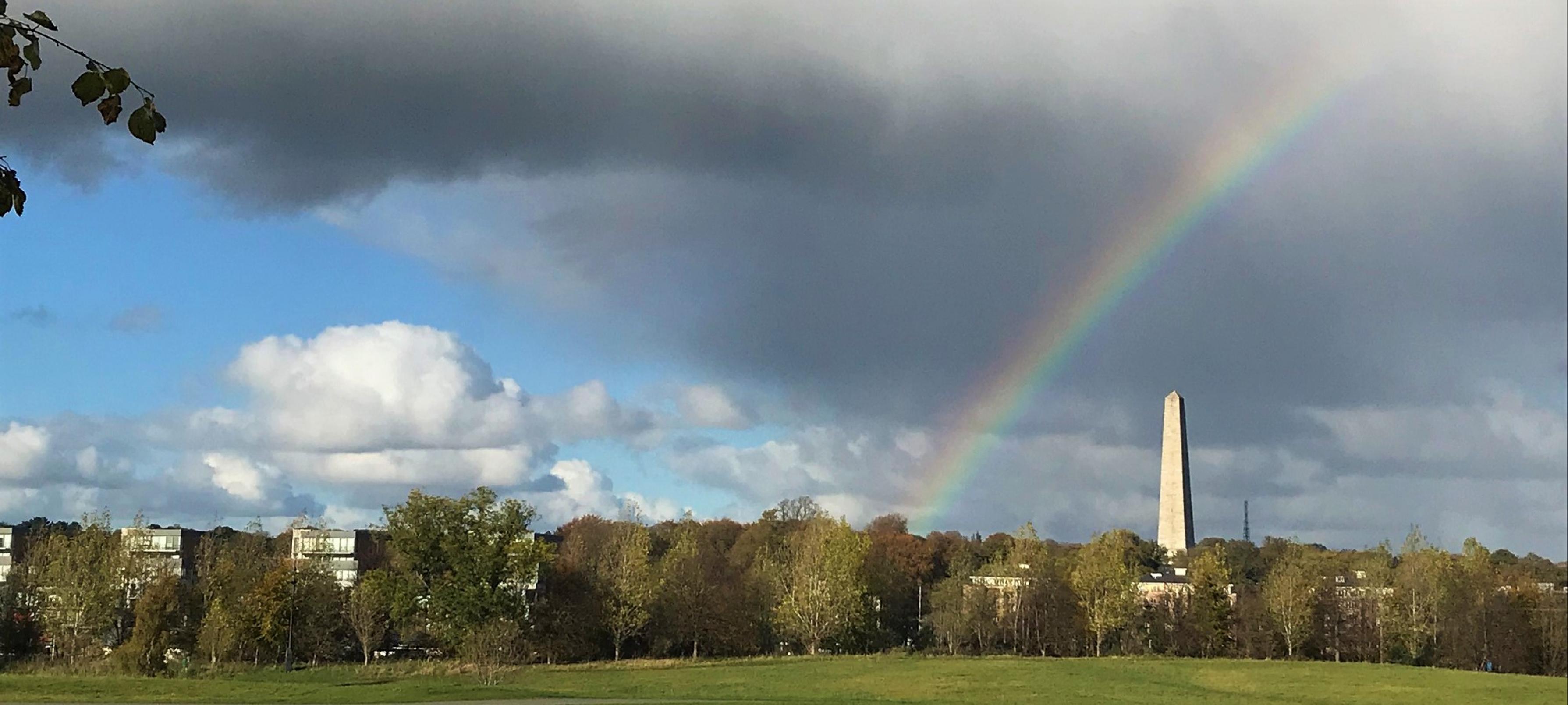 Ein Regenbogen wölbt sich über einem Obelisken am Himmel