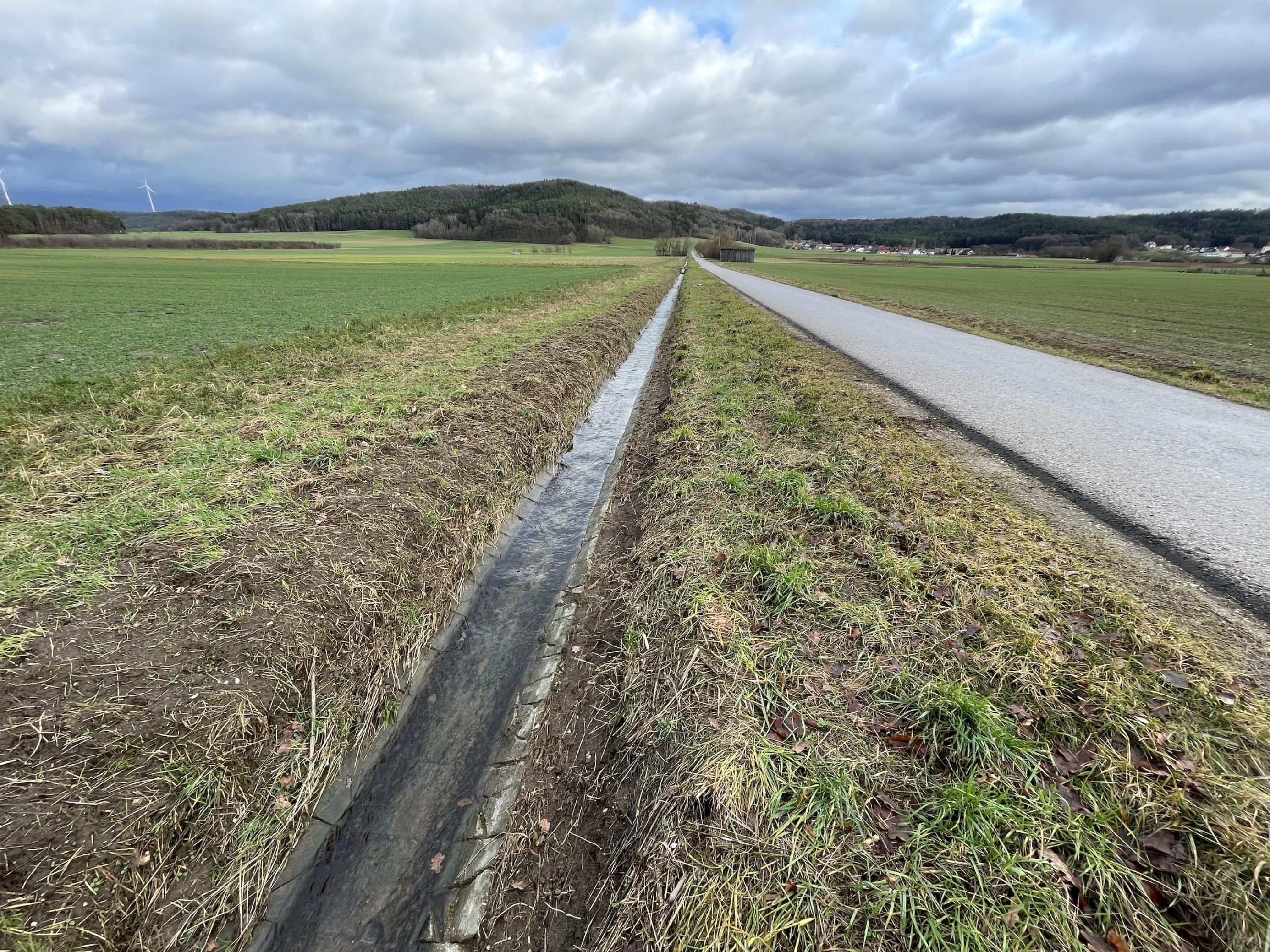 Ein schnurgerader Entwässerungsgraben, den von einem Feld nur wenige Meter ohne Vegetation trennen.